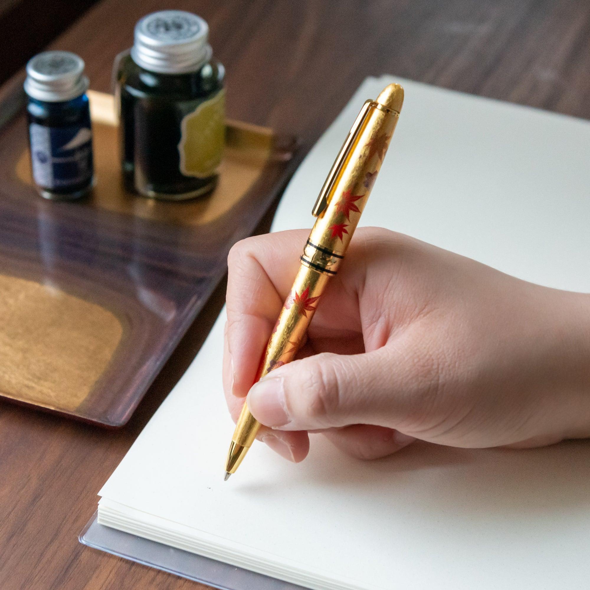 Capped and uncapped Gold Leaf Sakura and Momiji Makie ballpoint pen showing dual seasonal floral motifs