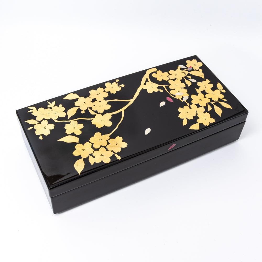Angled view of a black lacquer pen case featuring a gold sakura design with intricate petals, highlighting its refined Japanese artistry.