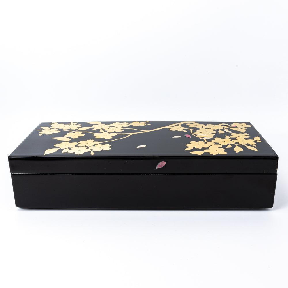 Front view of a black lacquer pen case adorned with gold sakura branches and petals, showcasing the refined artistry of Japanese stationery.
