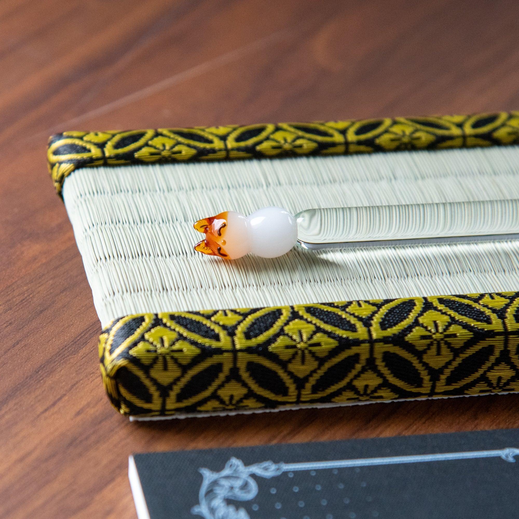 Pen holder detail showing natural straw texture and intricate gold shippo border trim design visible