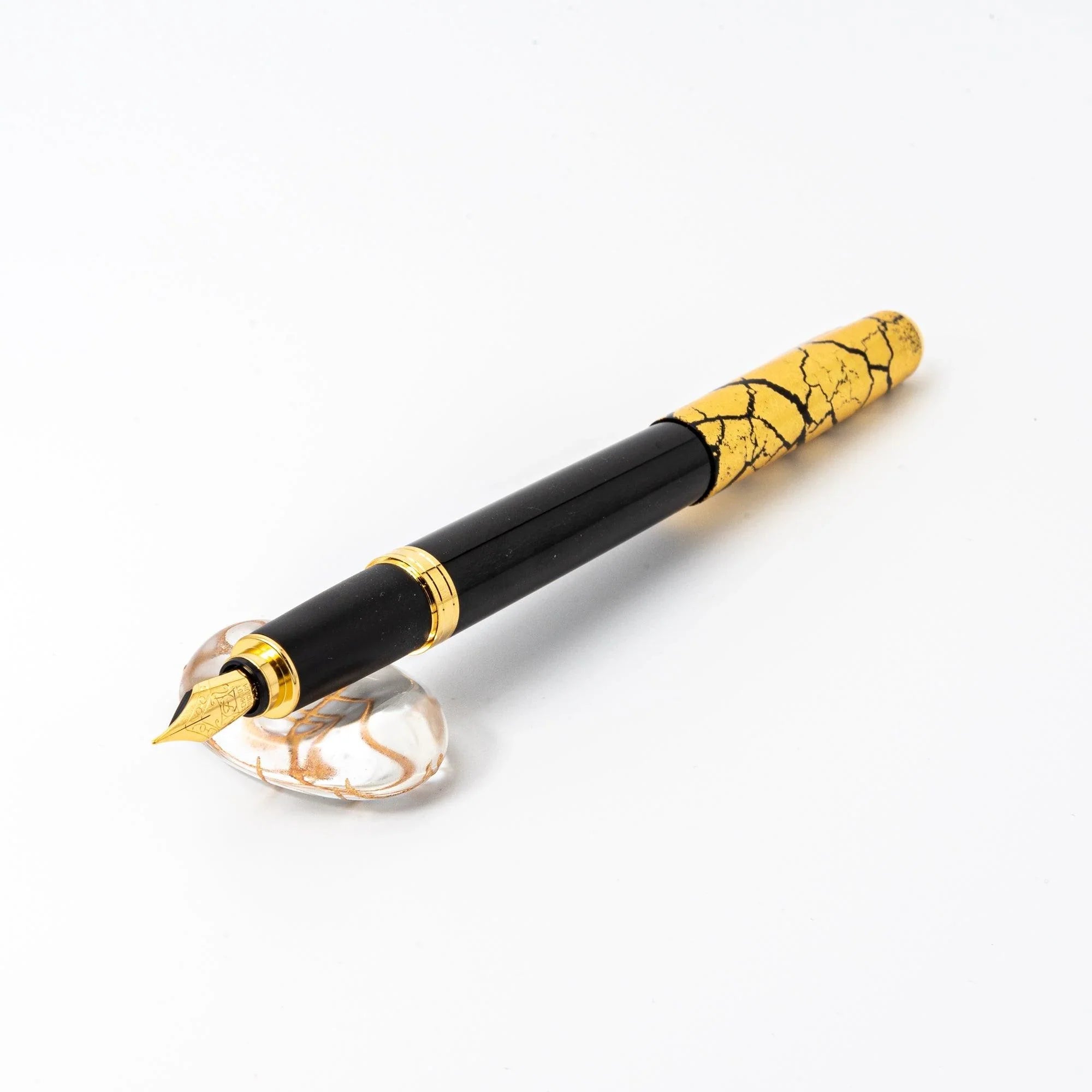 Japanese black lacquered dip pen with gold trim resting inside clear glass oval pen rest for product display composition