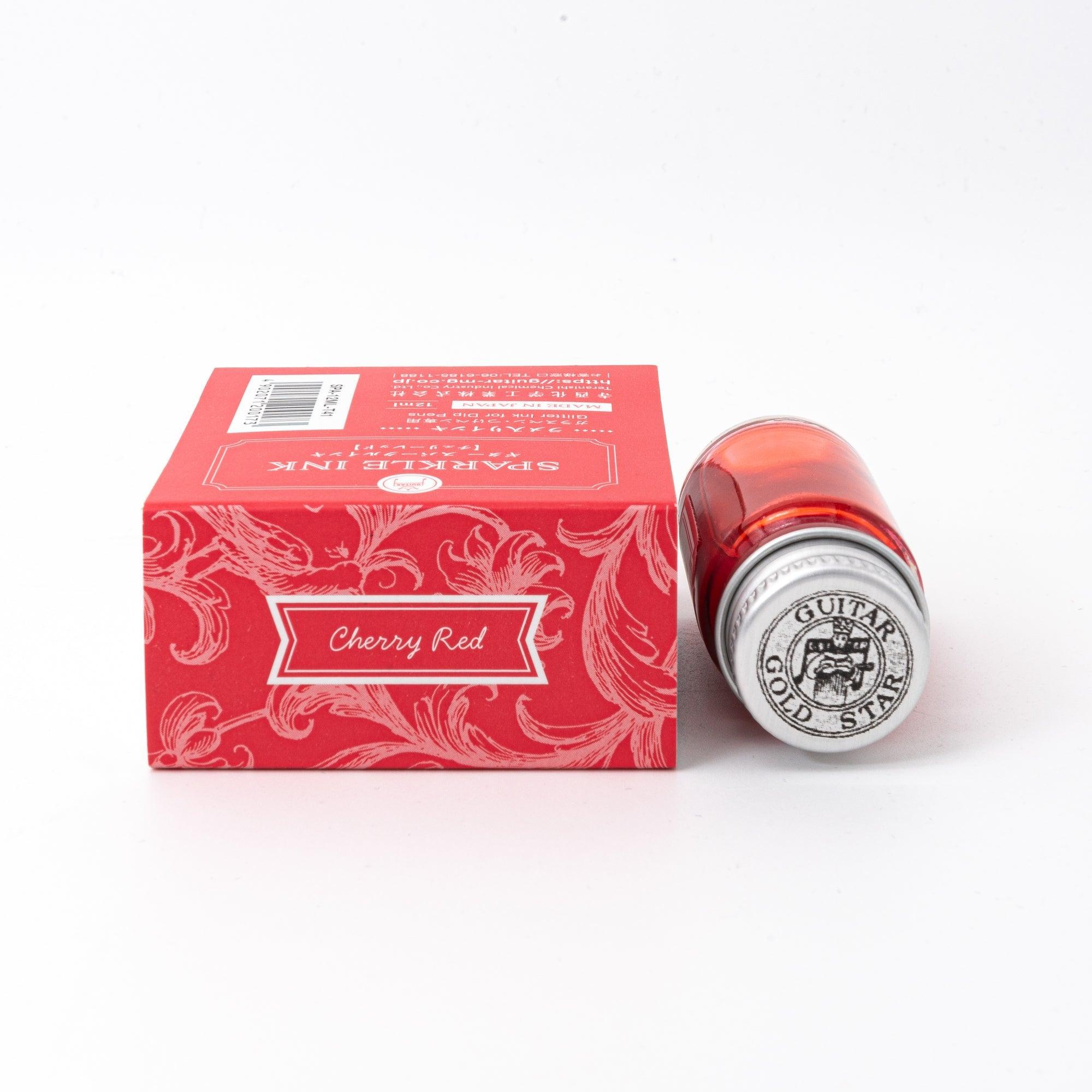 A bottle of Sparkle Ink in Cherry Red, accompanied by its matching red decorative box, adorned with intricate floral patterns.