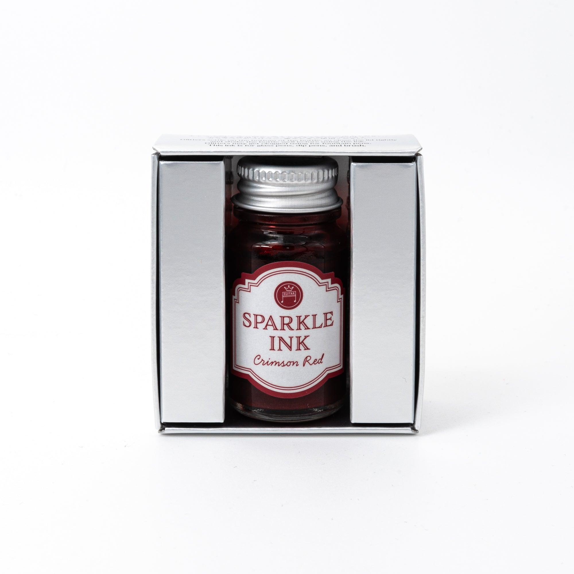 Sparkle Ink in Crimson Red, presented in a glass bottle with matching red packaging adorned with intricate floral patterns and elegant text.