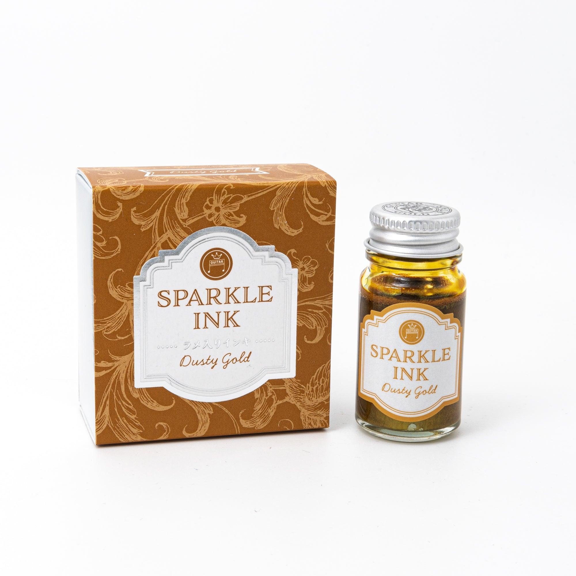 Sparkle Ink in Dusty Gold, packaged in a glass bottle paired with a golden box featuring intricate floral patterns and sophisticated typography.