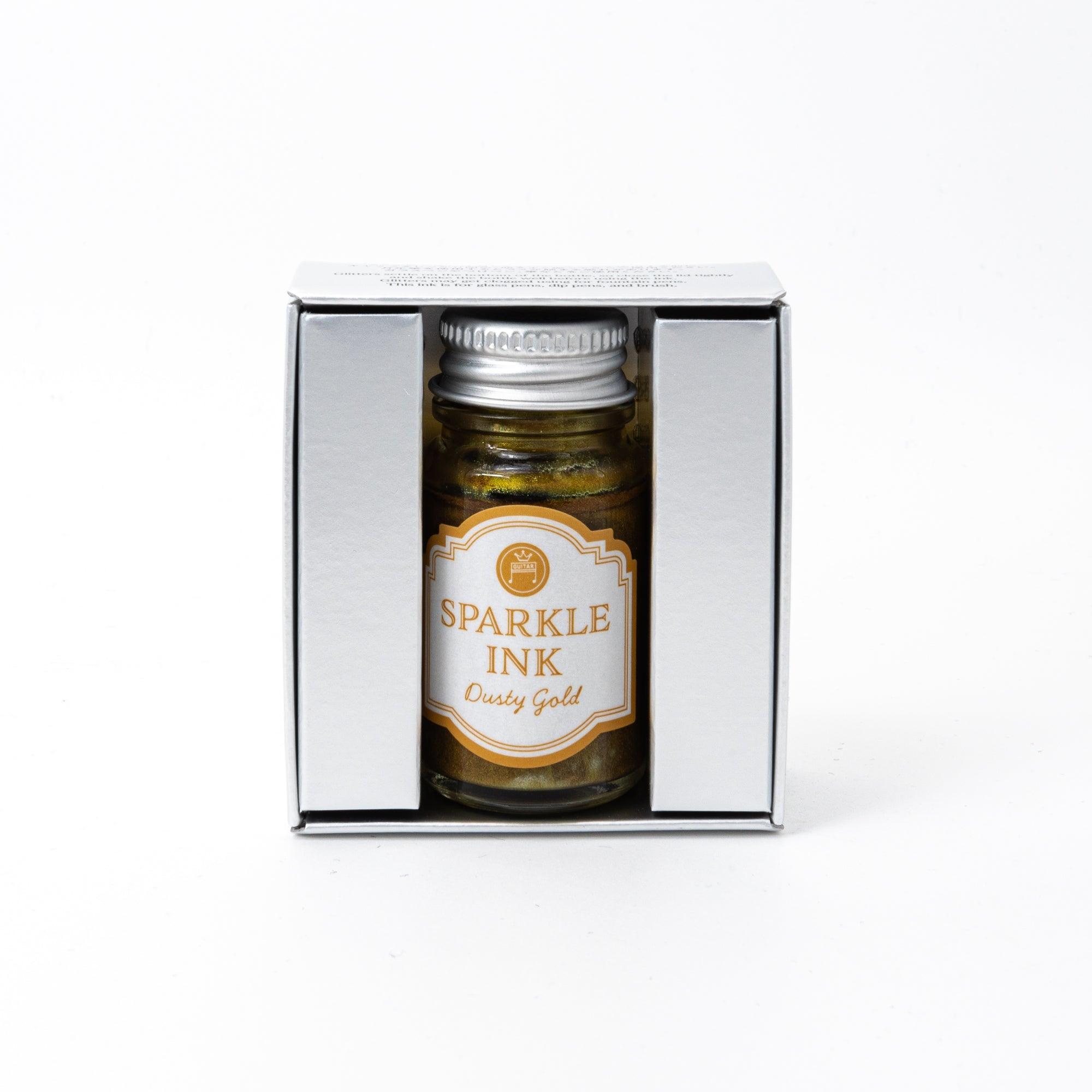 Sparkle Ink in Dusty Gold, packaged in a glass bottle paired with a golden box featuring intricate floral patterns and sophisticated typography.