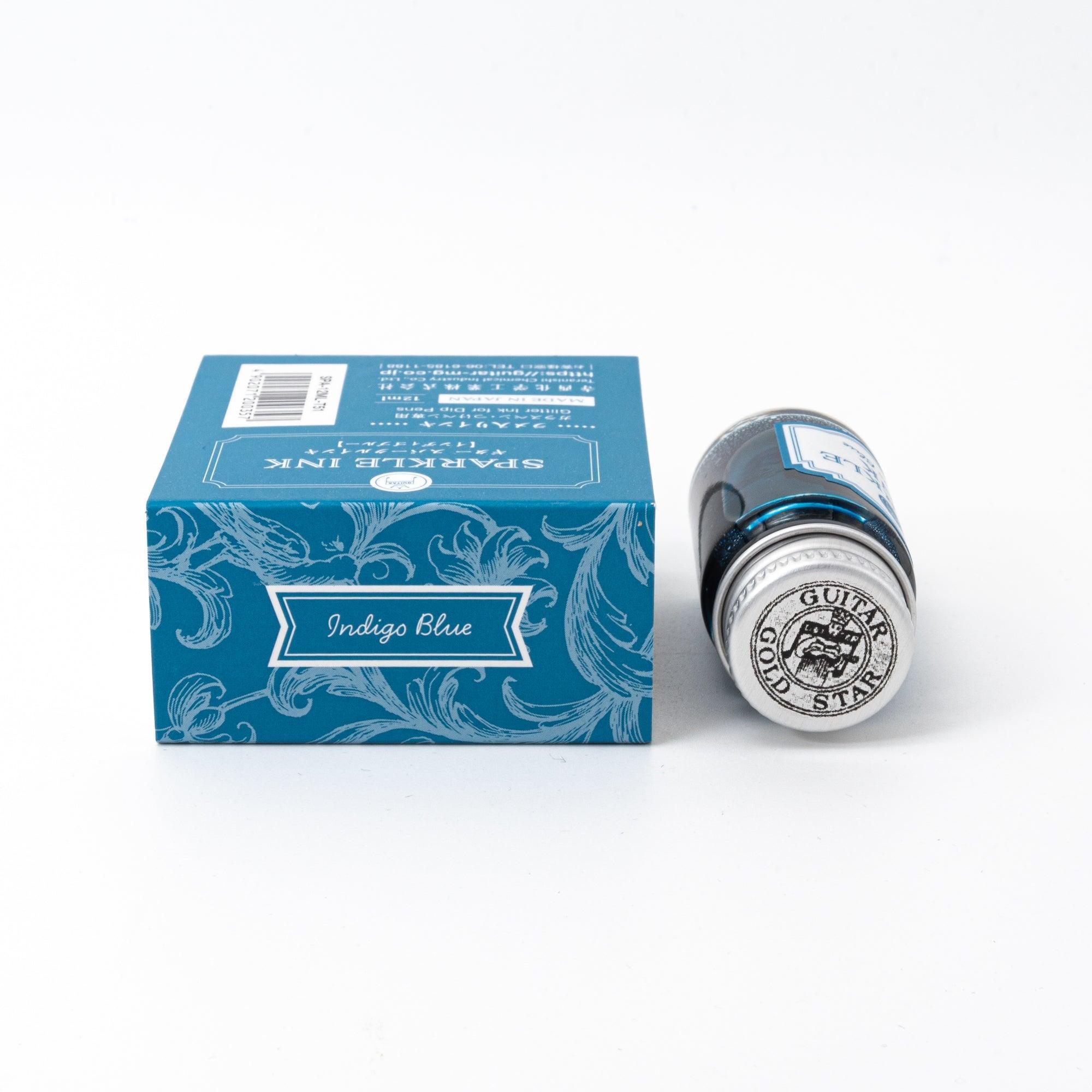 Sparkle Ink in Indigo Blue, showcased in a glass bottle with matching blue packaging featuring elegant floral designs and refined typography.