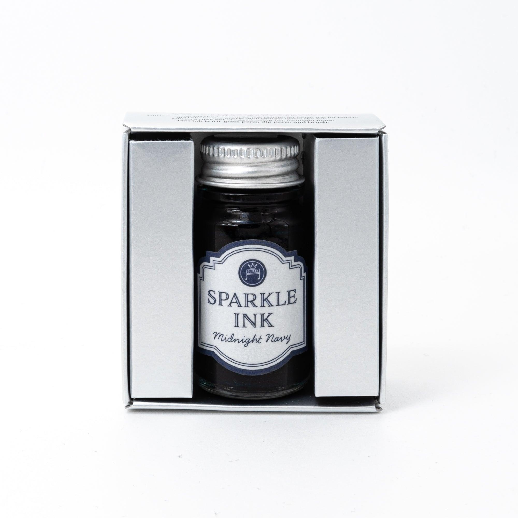 Sparkle Ink in Midnight Navy, presented in a glass bottle with a matching navy box, adorned with elegant floral patterns and refined typography.