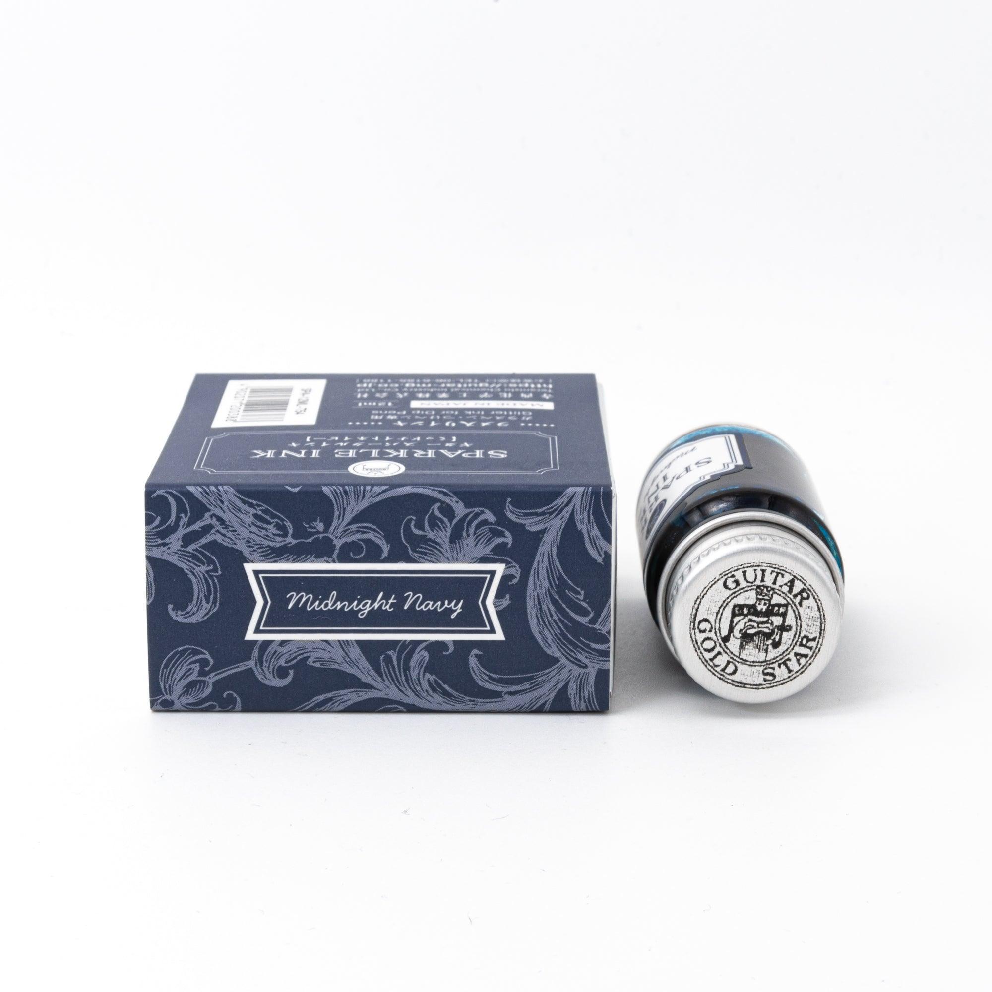 Sparkle Ink in Midnight Navy, presented in a glass bottle with a matching navy box, adorned with elegant floral patterns and refined typography.