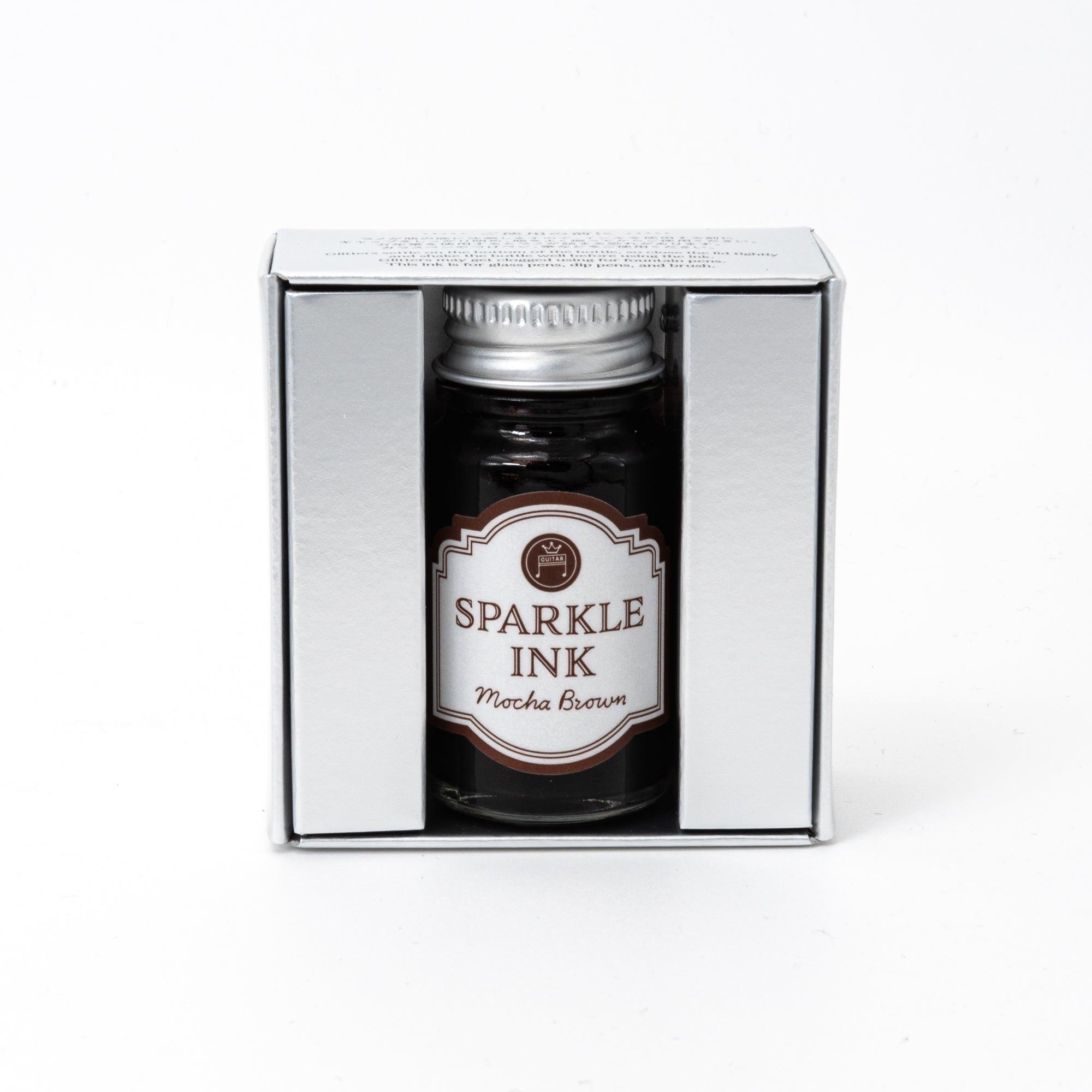 Sparkle Ink in Mocha Brown, presented in a glass bottle with elegant packaging adorned with floral patterns in rich brown tones.