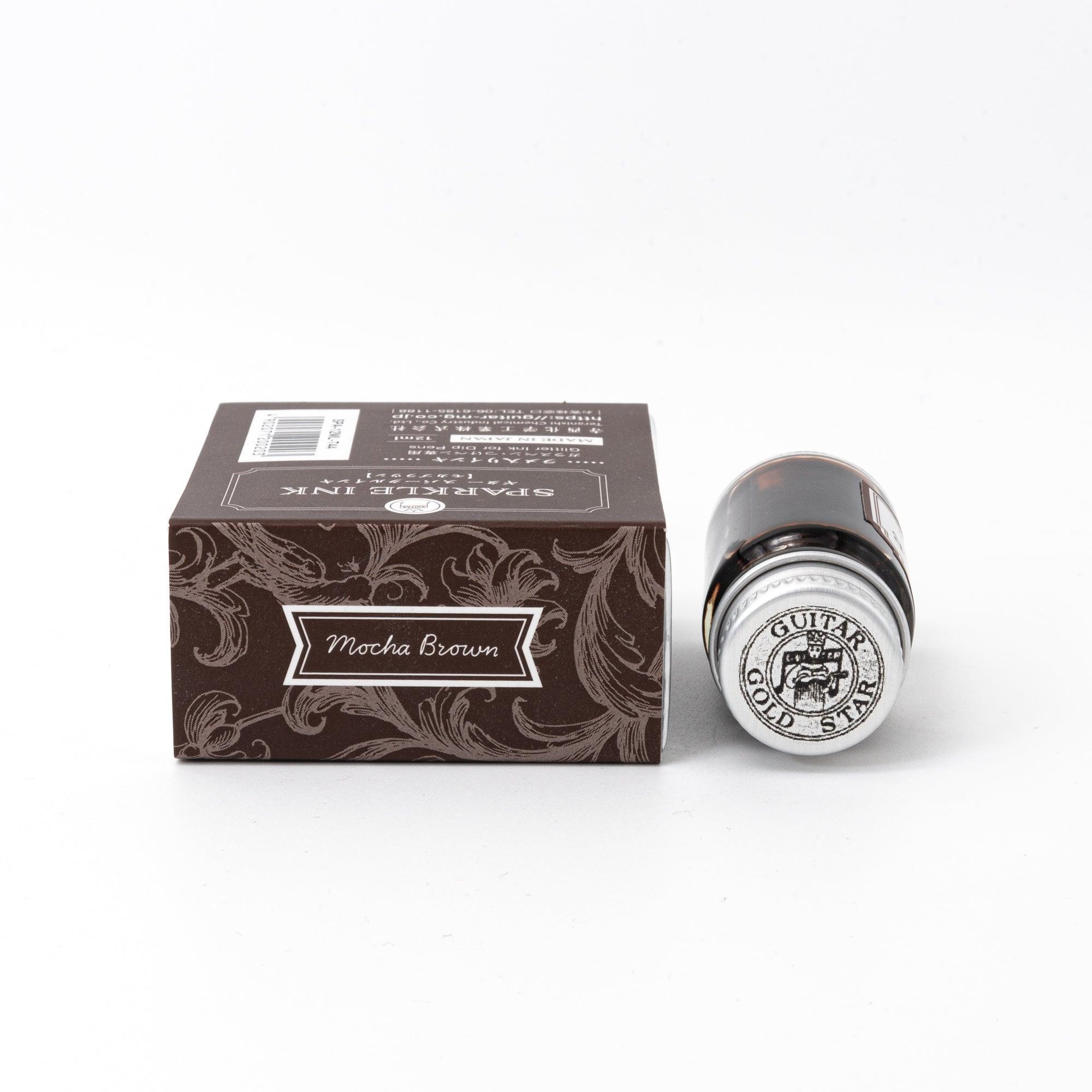 Sparkle Ink in Mocha Brown, presented in a glass bottle with elegant packaging adorned with floral patterns in rich brown tones.