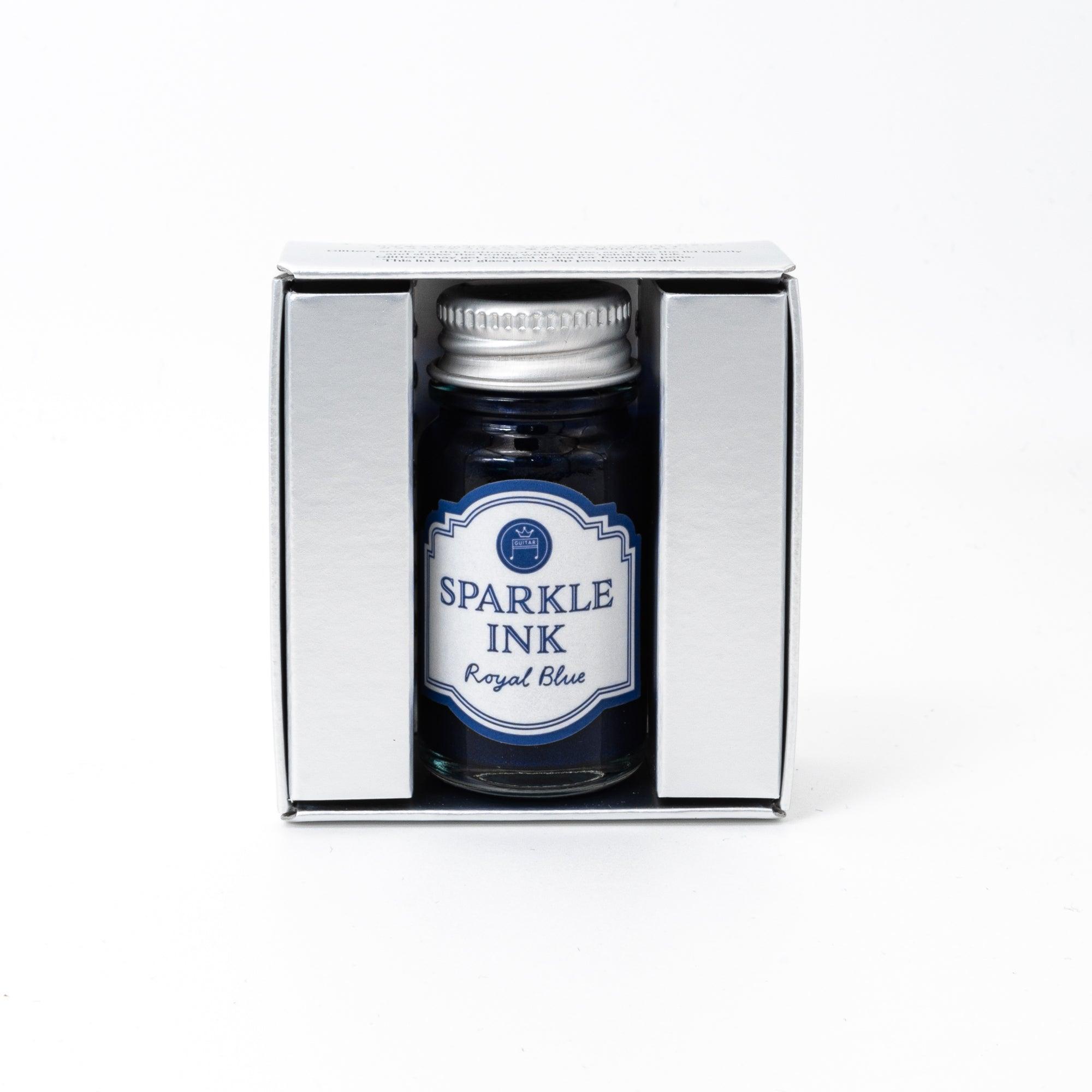 Sparkle Ink in Royal Blue, displayed in a glass bottle with elegant packaging featuring floral patterns in matching blue tones.