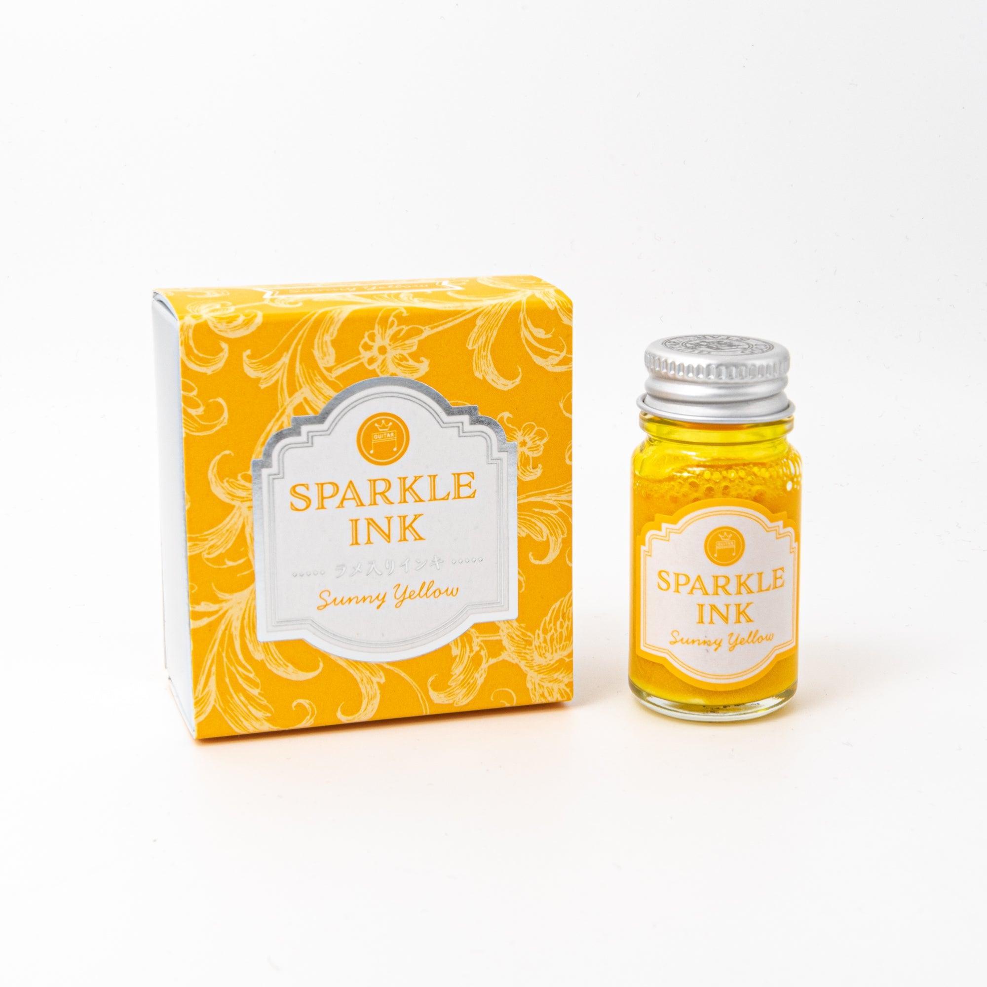 Sparkle Ink in Sunny Yellow, presented in a glass bottle with coordinating yellow packaging adorned with intricate floral designs and elegant text.