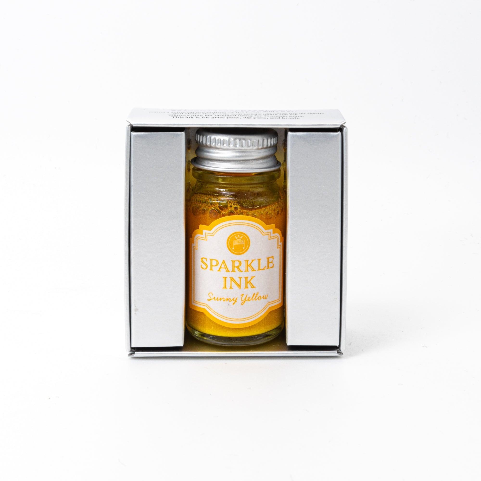 Sparkle Ink in Sunny Yellow, presented in a glass bottle with coordinating yellow packaging adorned with intricate floral designs and elegant text.