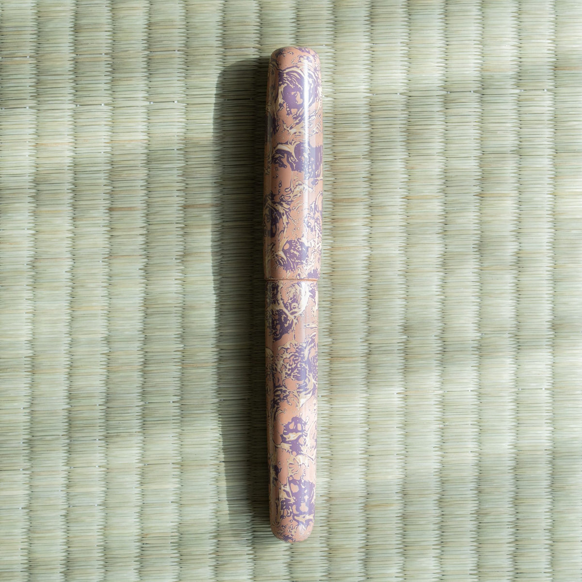 Hanagasumi Tsugaru-nuri urushi fountain pen, capped, pale pink lacquer with a purple pattern, on a tatami mat