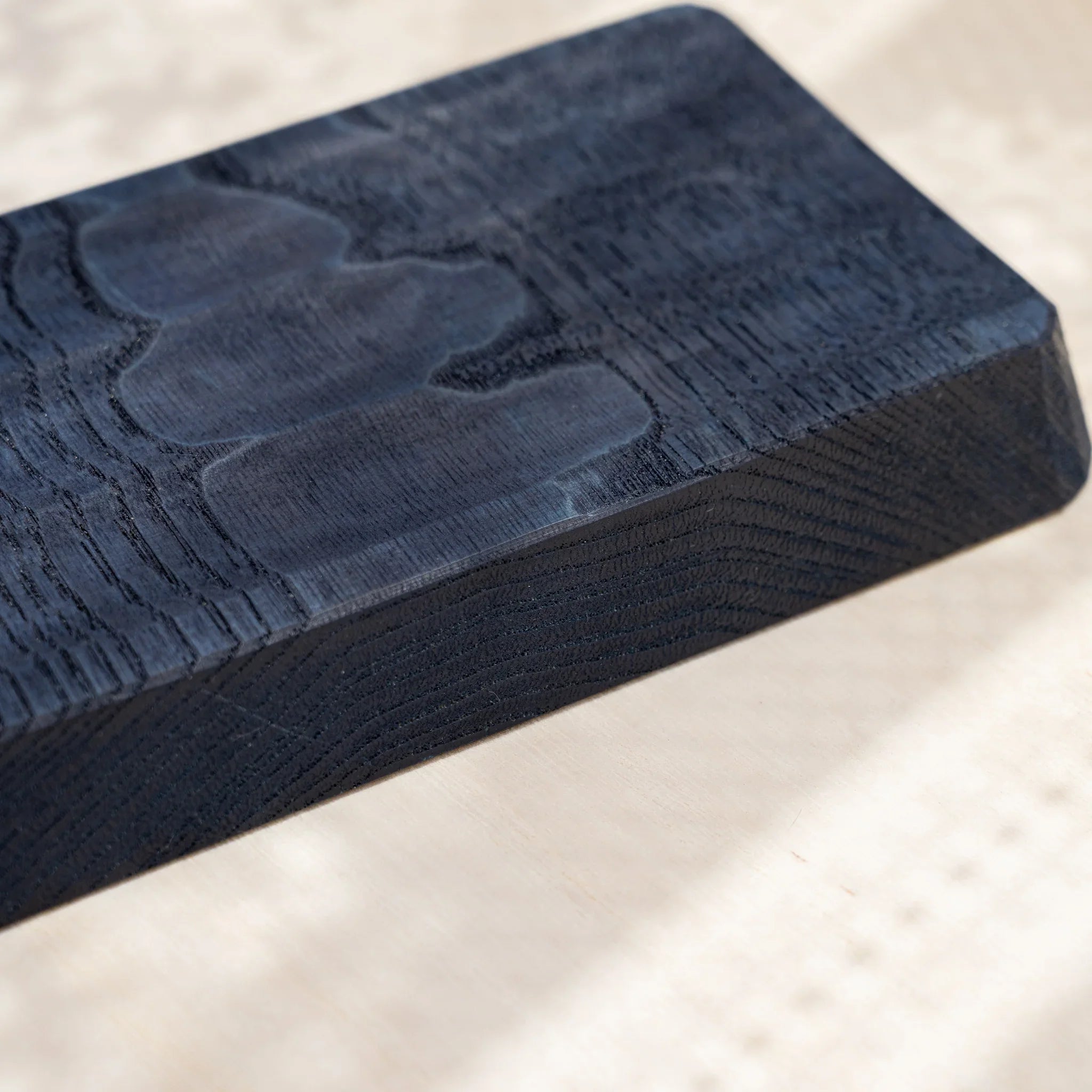 Angled close-up of an indigo dyed slim chestnut pen tray corner showing the beveled edge, thickness and grain