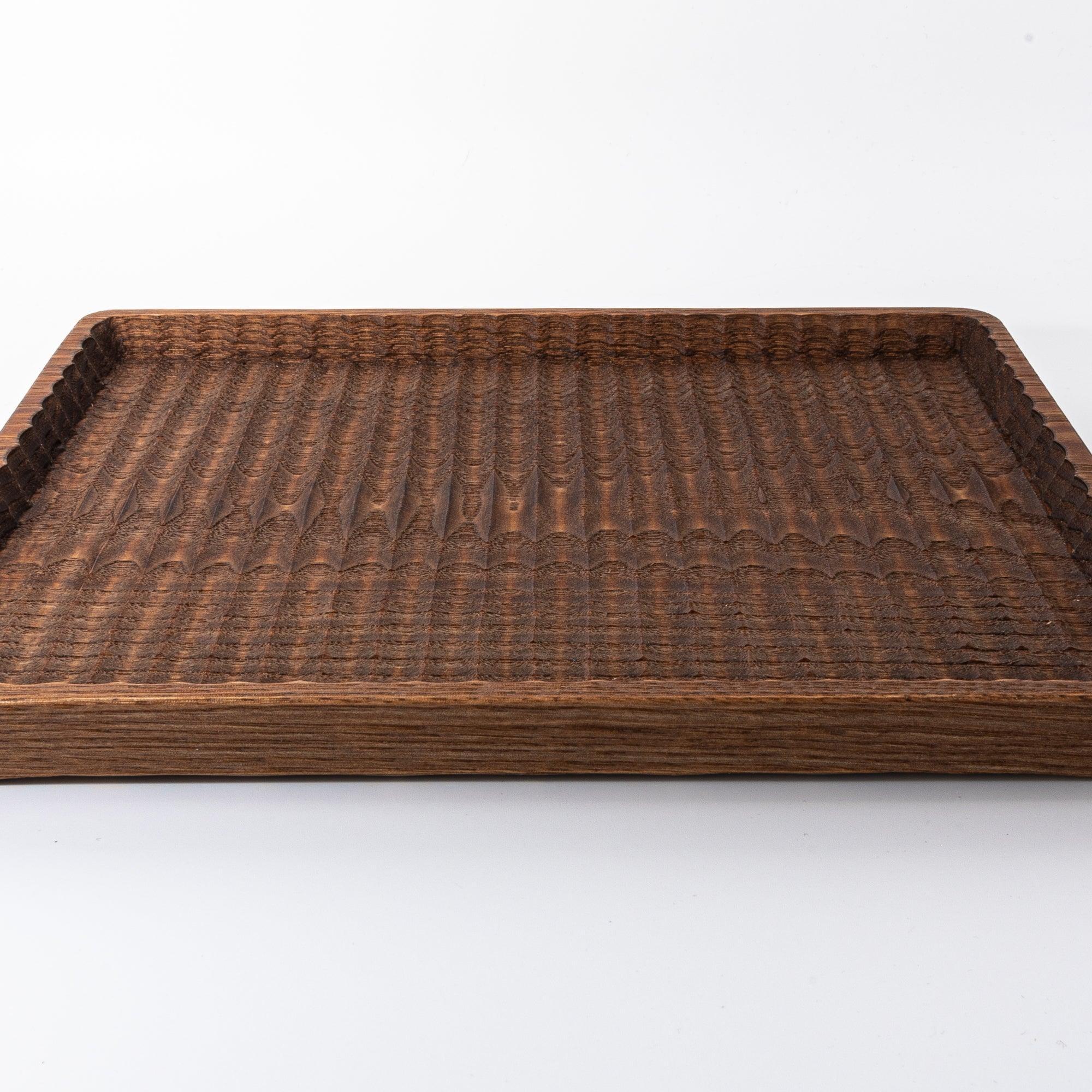Dark wooden tray with a raised edge and carved surface, shown on a white backdrop.