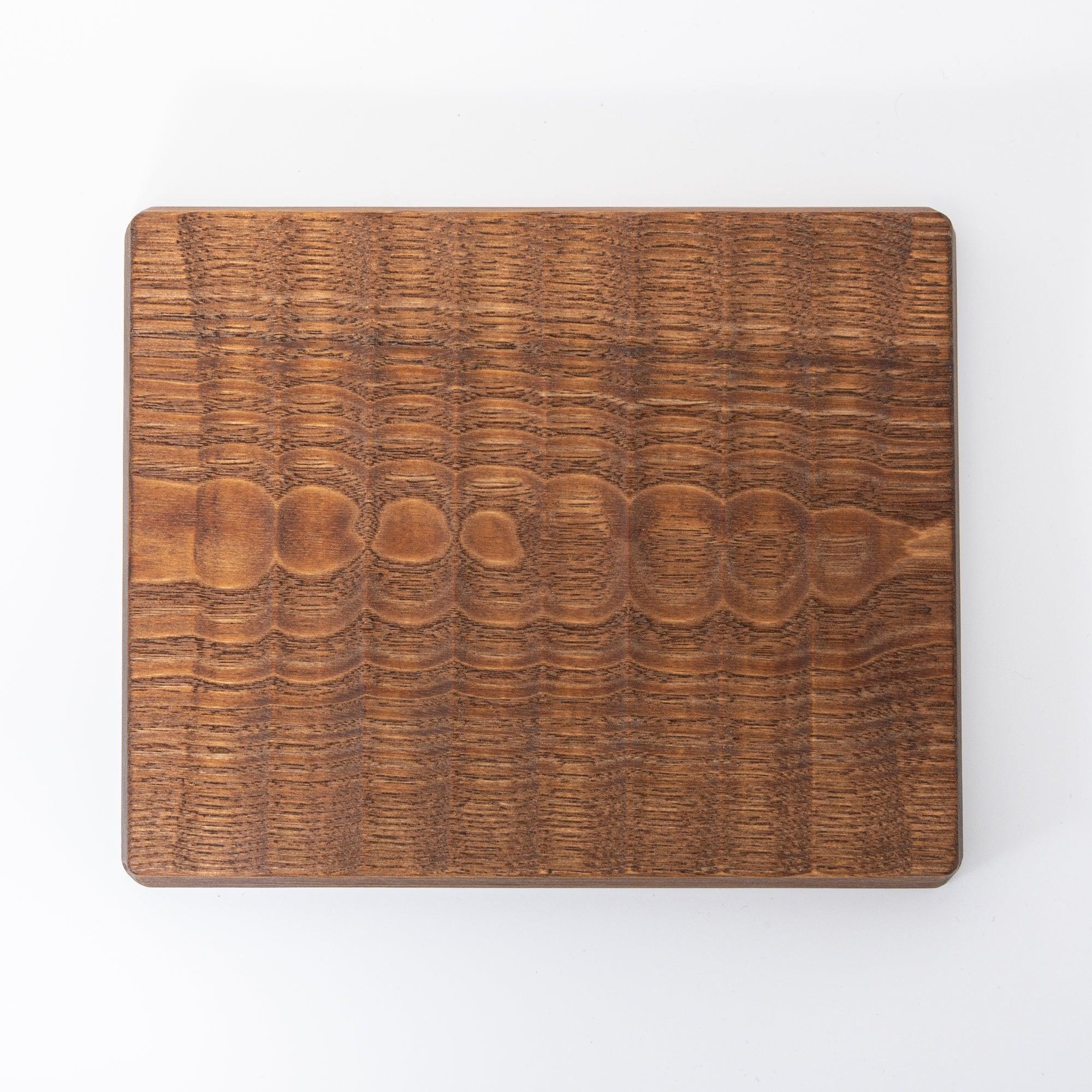 Dark brown wooden board with a smooth surface and visible natural grain patterns, shown against a white background.