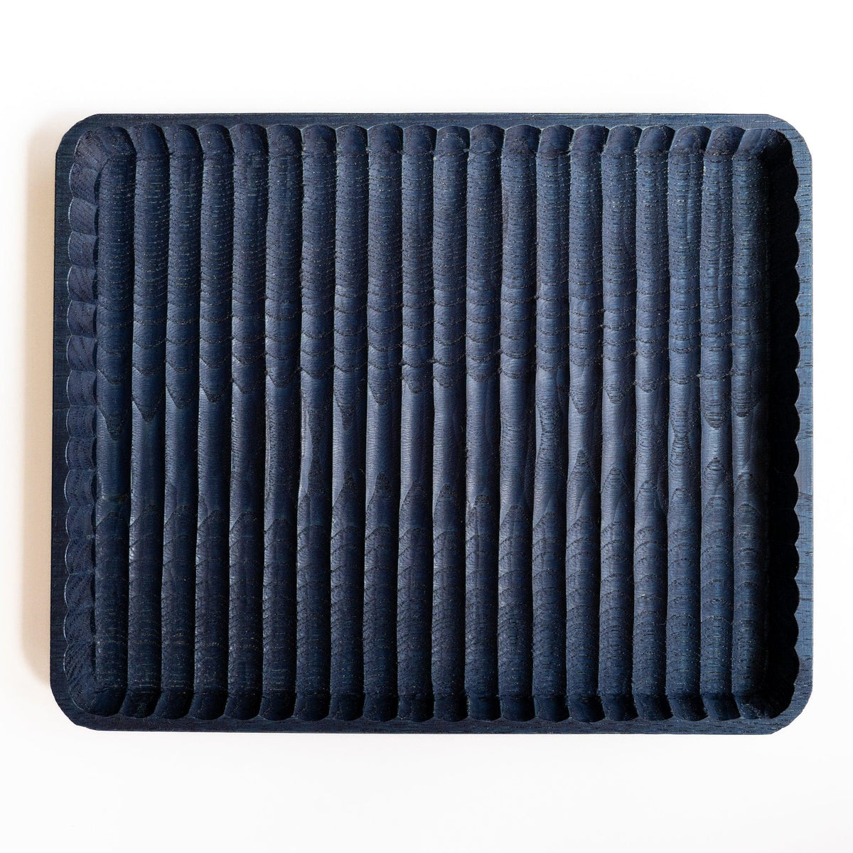 Empty indigo dyed wide Wagatabon chestnut pen tray from above with parallel hand-carved grooves and scalloped rim