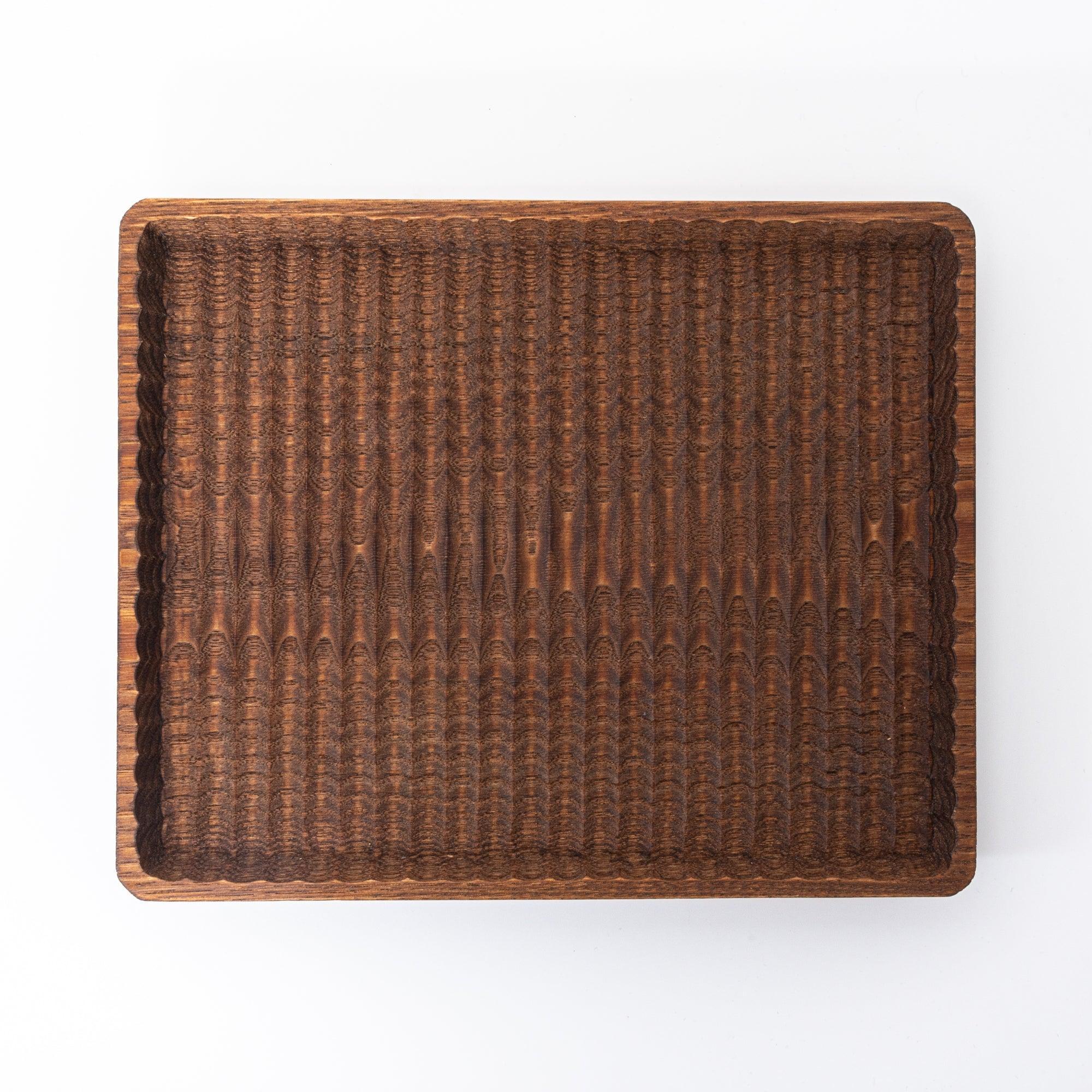 A dark wooden tray with intricate carved grooves, displayed flat against a white background.