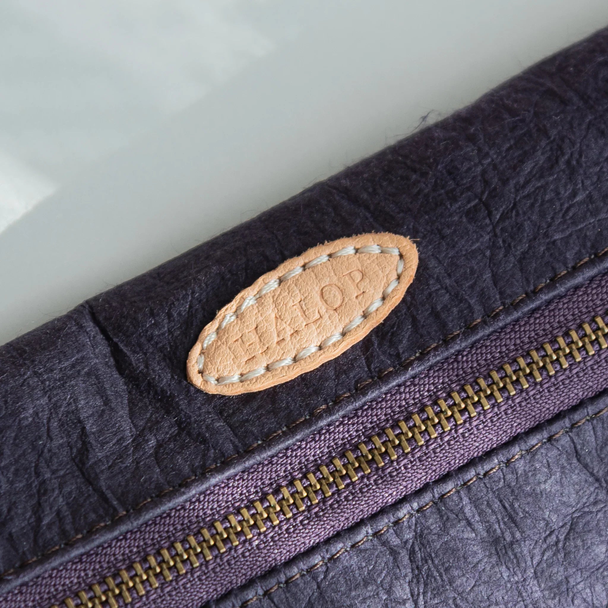 Close-up of the leather “HALOP” tag stitched on the purple Sugihara Washi Japanese Pen Case.