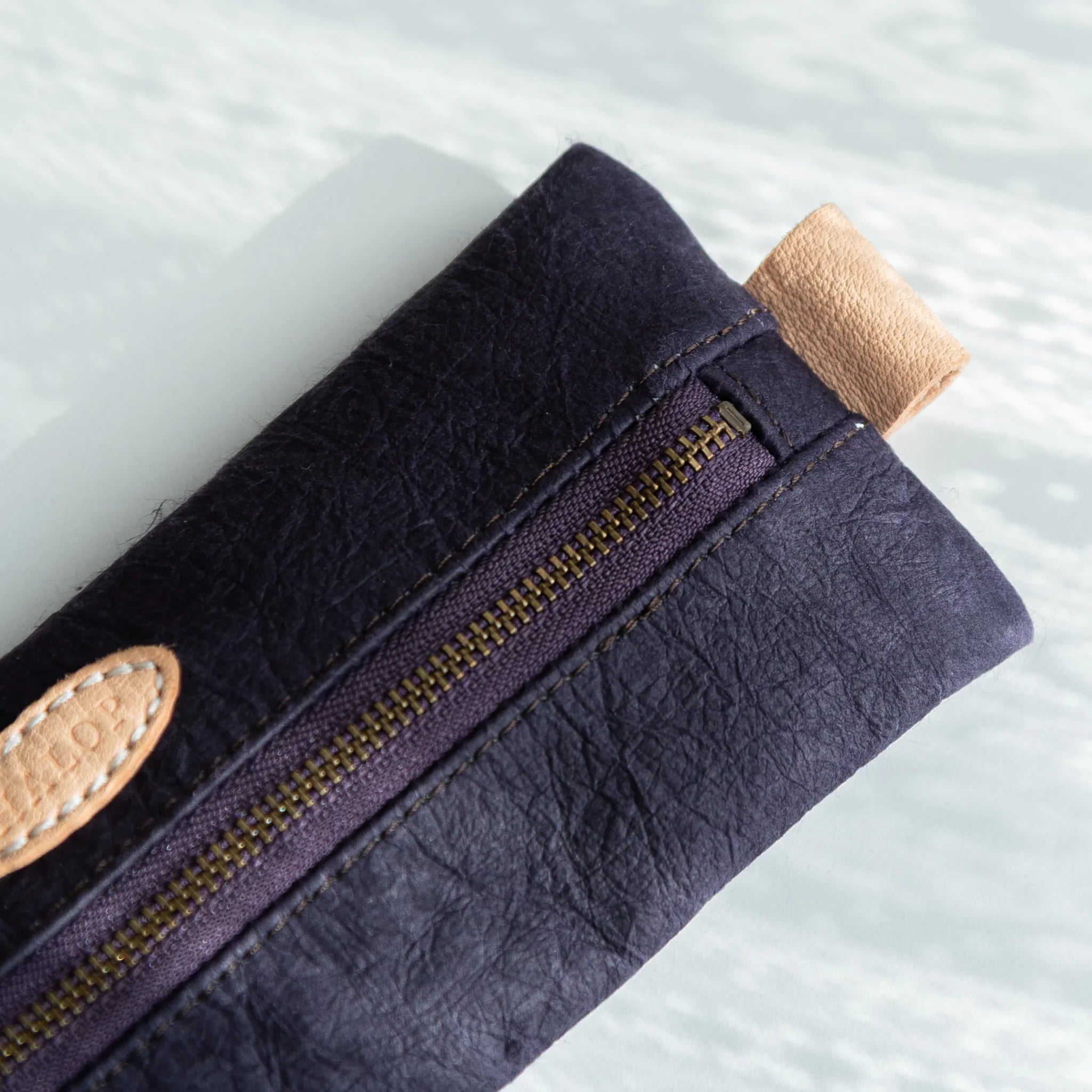 Detailed view of the right end of the Japanese Pen Case, highlighting the beige leather pull and textured purple washi surface.