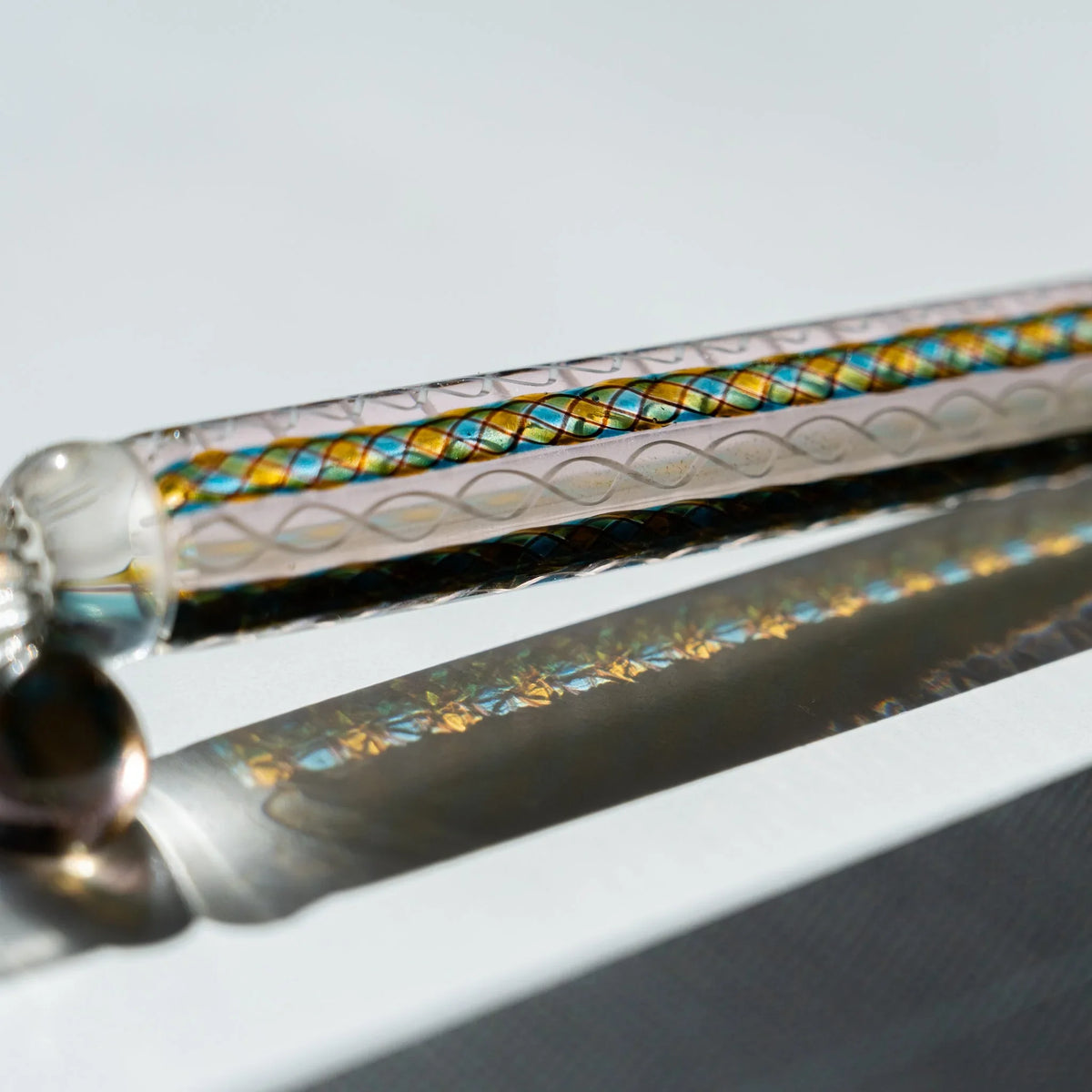 Close-up of the Helix Peacock barrel showing teal and gold diamond canes beside white spiral twists