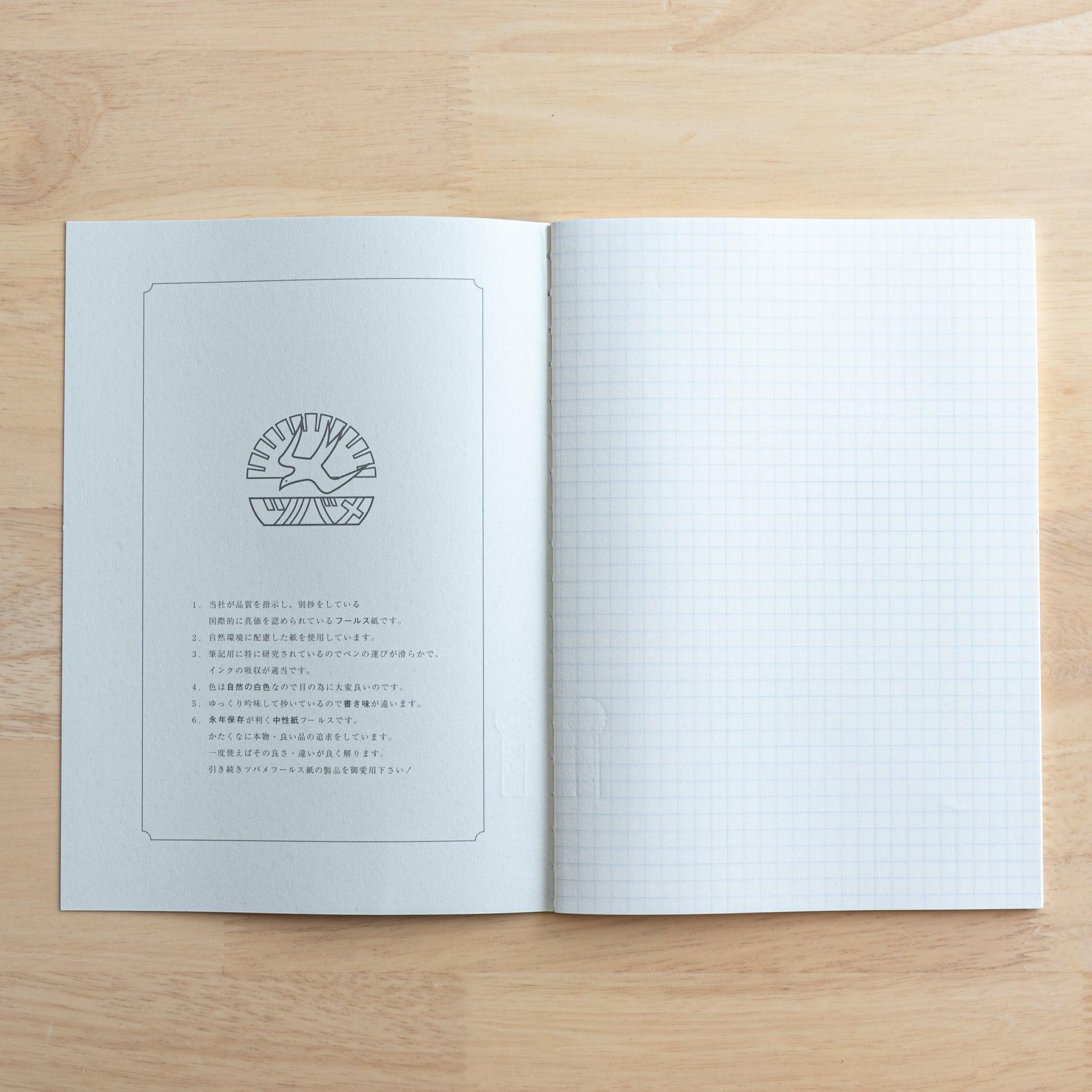 An open Tsubame Japanese notebook with a Hello Kitty design, displaying a brand logo page on the left and high-quality grid paper on the right, showcasing fine Japanese stationery.
