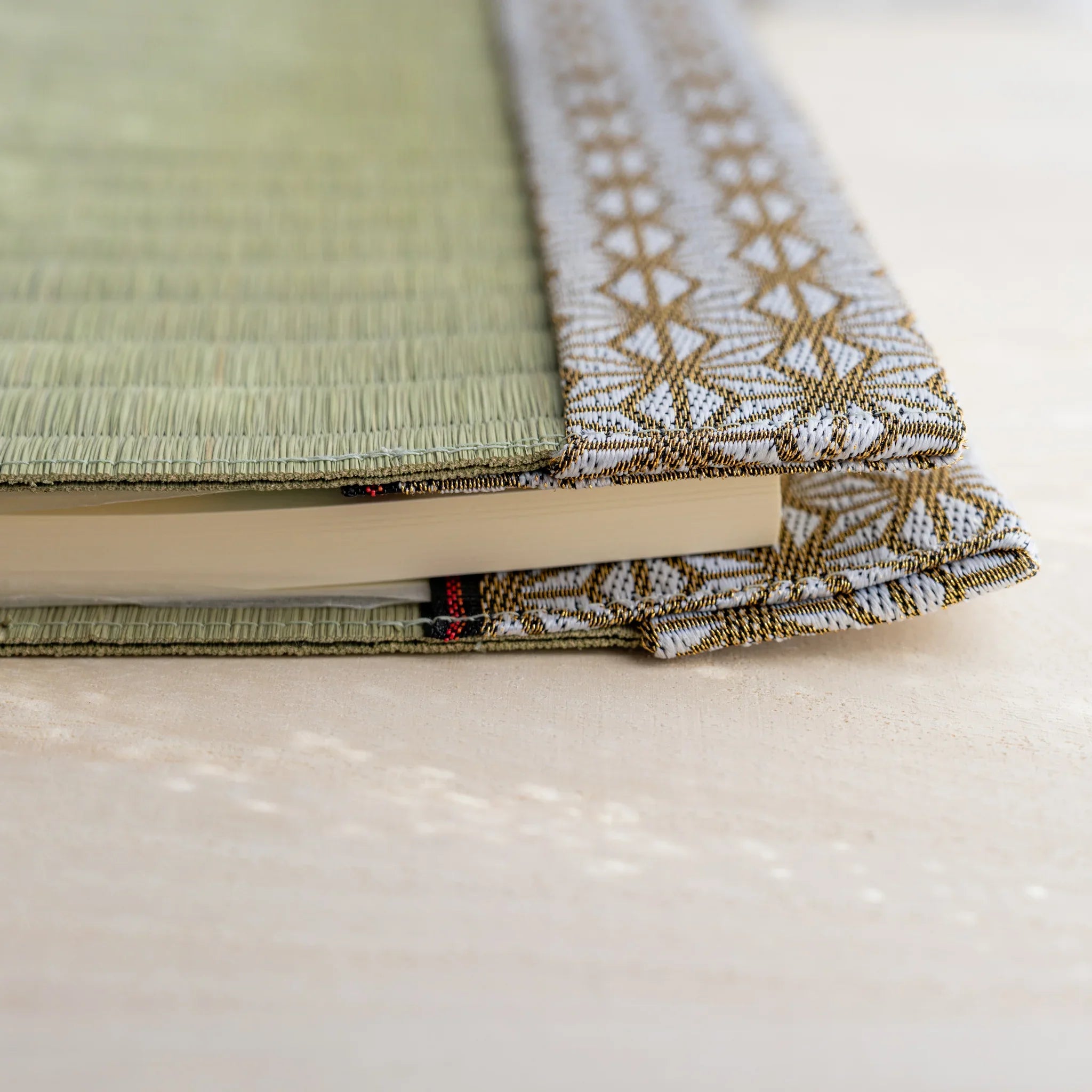Side view of tatami book cover with notebook inserted, showing thickness and folded hemp leaf pattern fabric flap
