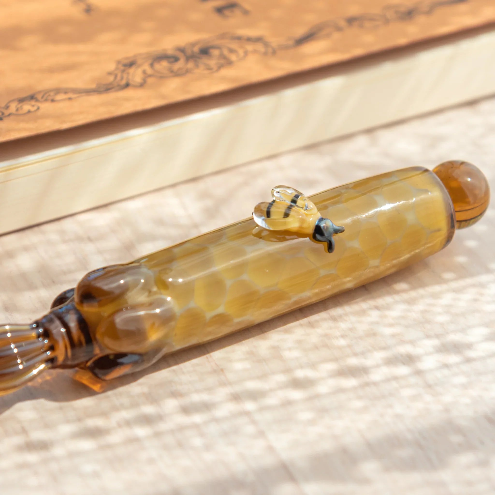 Glass dip pen with honey bee design on vibrant hand-blown glass and textured ceramic sand base with unique design