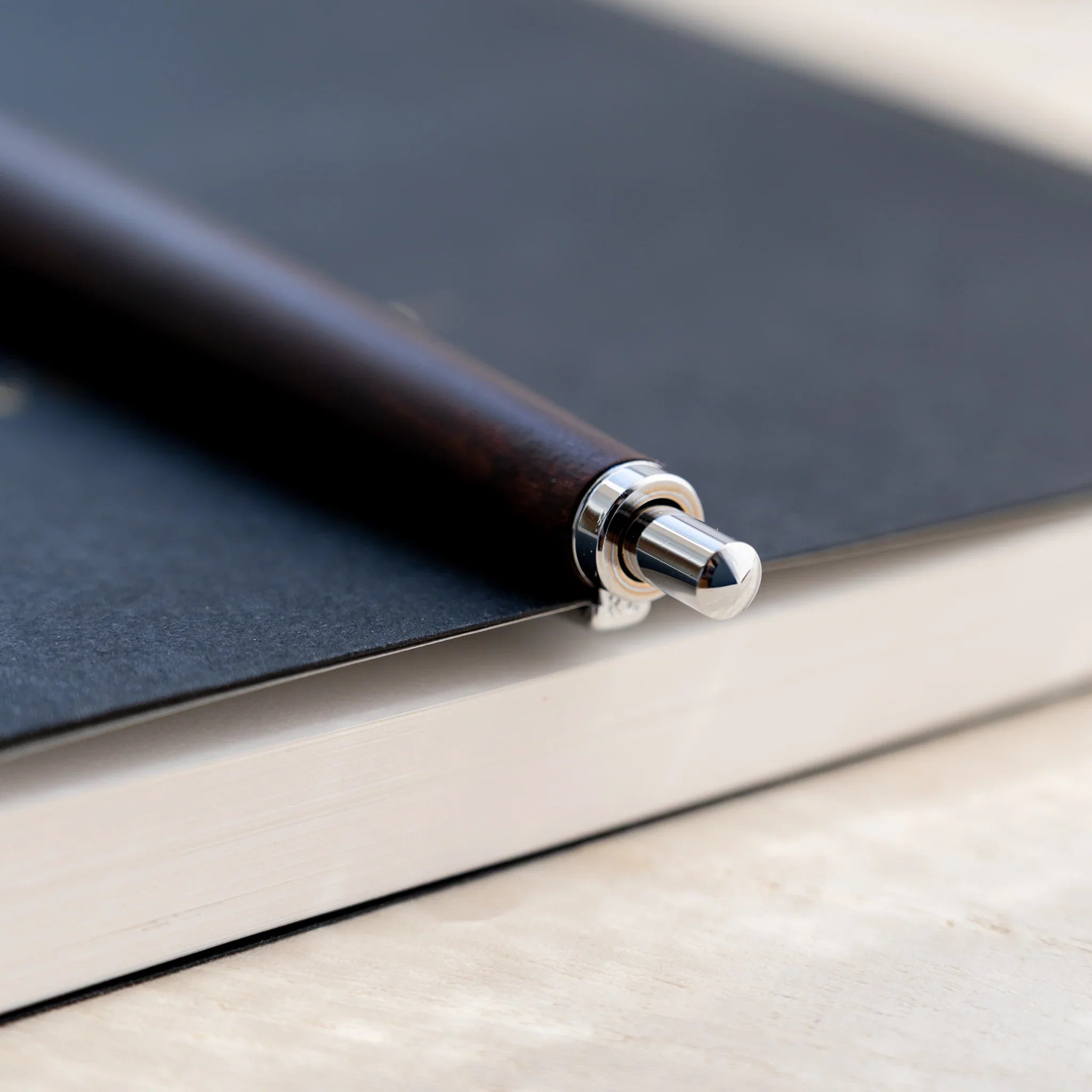 Chocolate brown horse chestnut wood urushi ballpoint pen, close-up of knock end and silver clip, Japanese wood