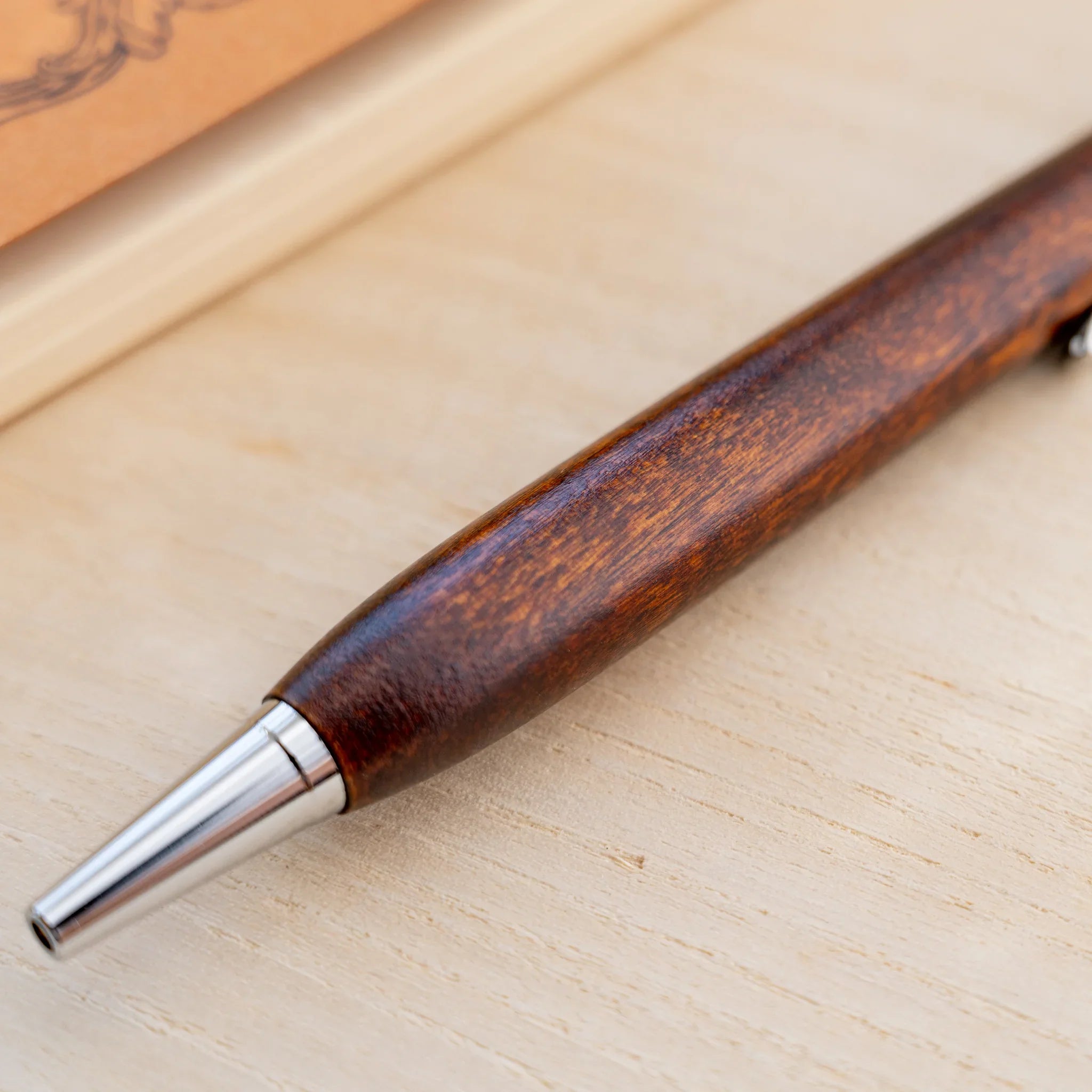 Amber-brown horse chestnut wood urushi ballpoint pen, close-up of barrel wood grain and silver clip, Japanese wood