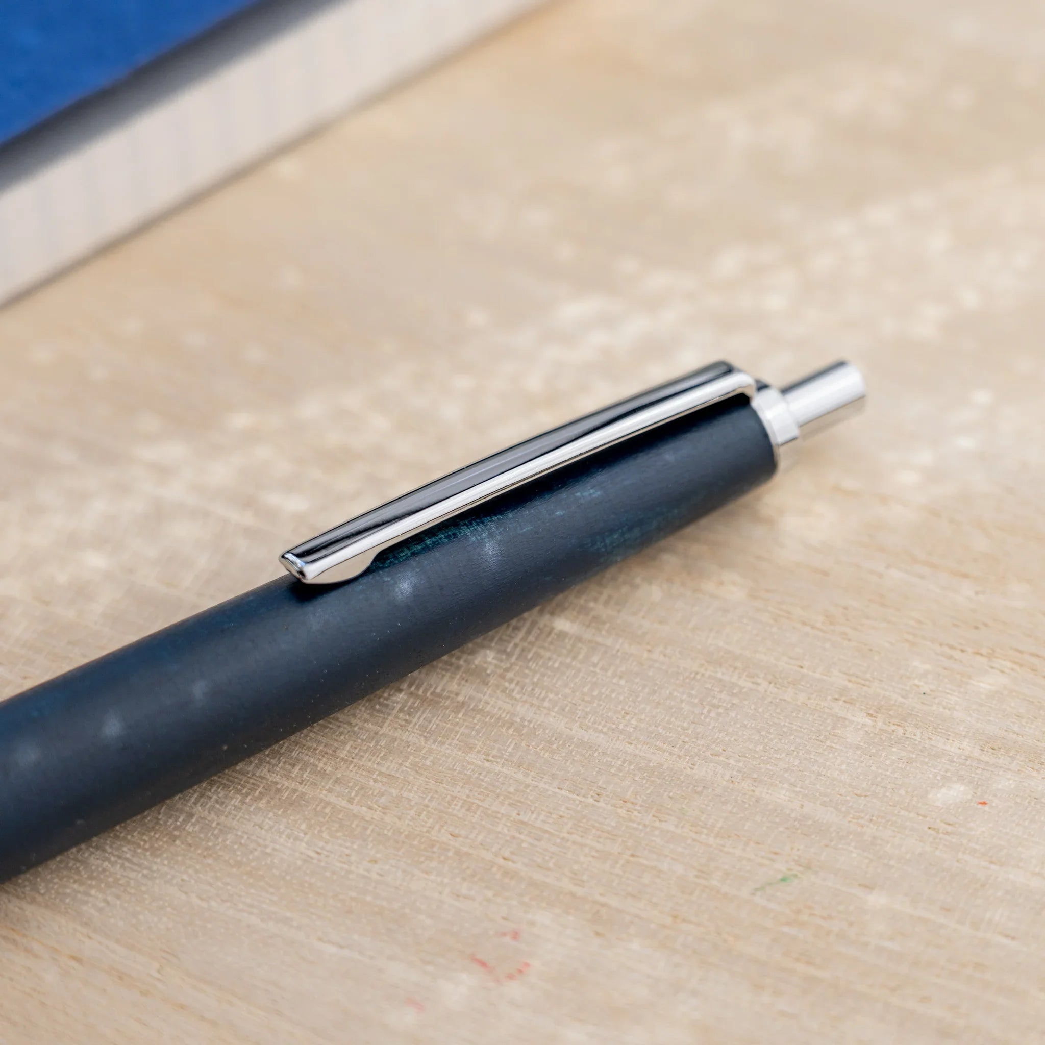 Indigo blue horse chestnut wood urushi ballpoint pen, close-up of knock end and silver clip, Japanese wood