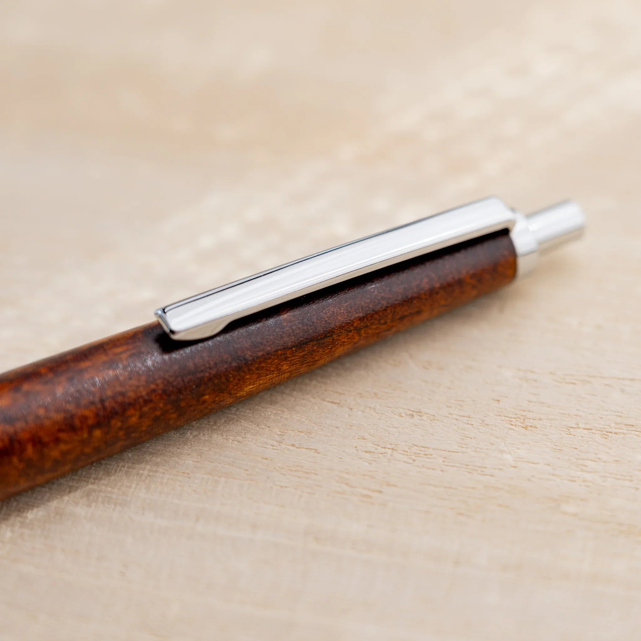 Amber-brown horse chestnut wood urushi ballpoint pen, close-up of knock end and silver clip, Japanese wood