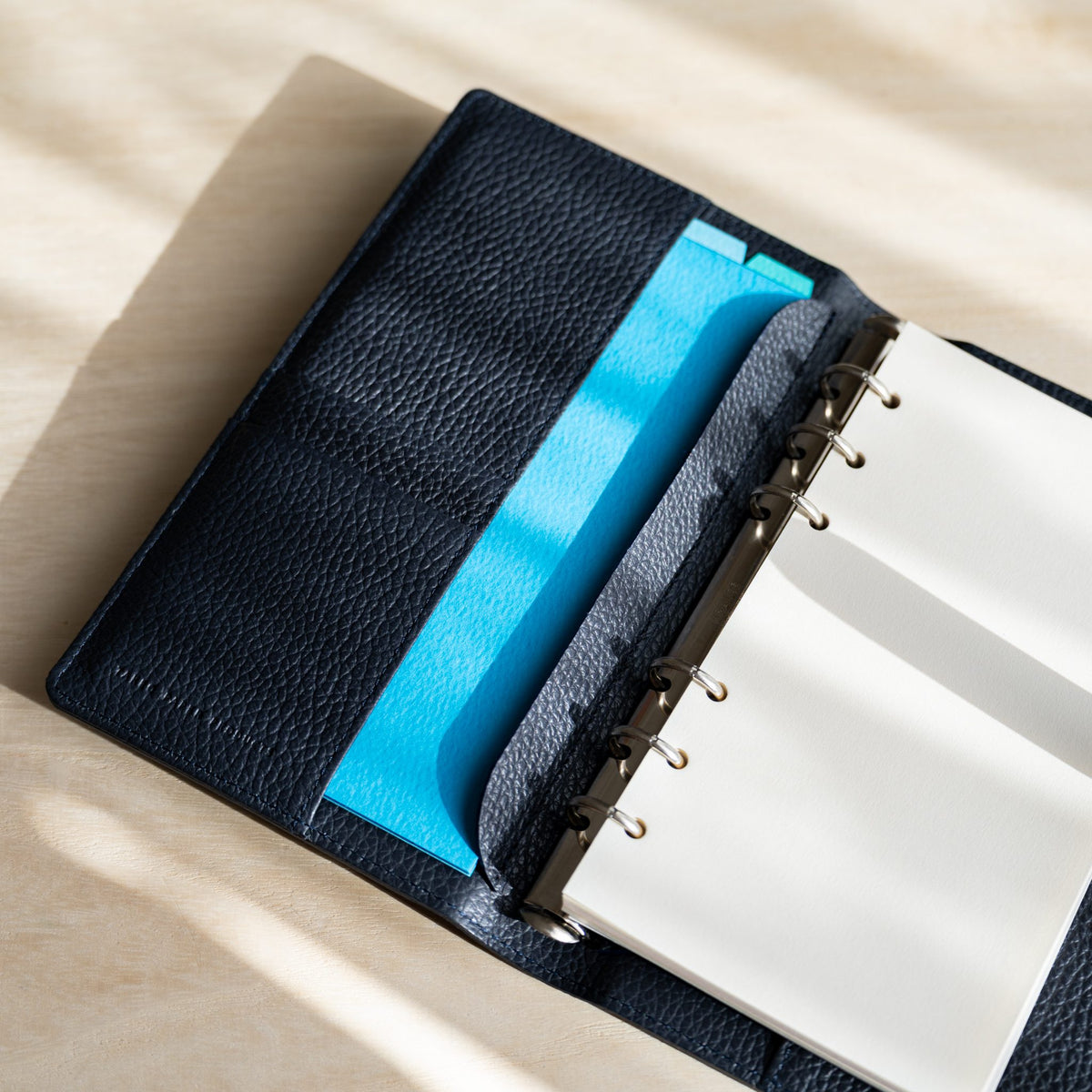 Sky blue sheet in the inner pocket of the navy planner opposite white pages on silver rings