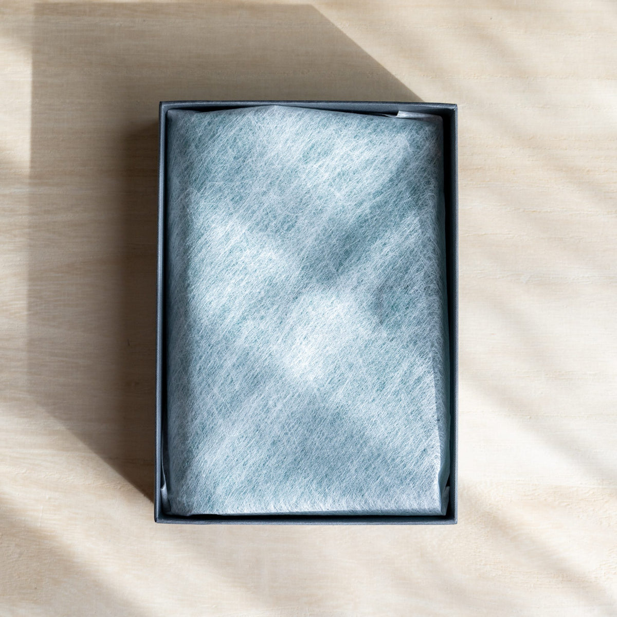 Open gray box with the planner under a white nonwoven wrap