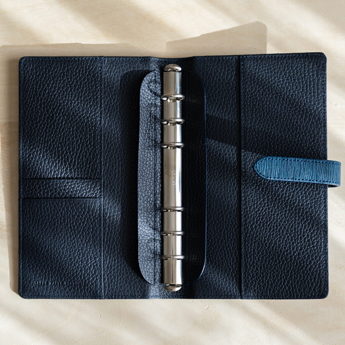 Navy Ise Gikakushi planner opened flat, navy leather interior, silver rings and card pockets