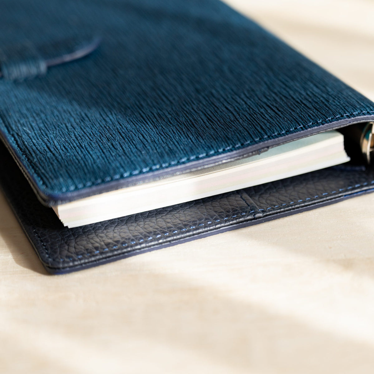 Navy Ise Gikakushi planner partly closed, cream pages between the creased cover and navy lining