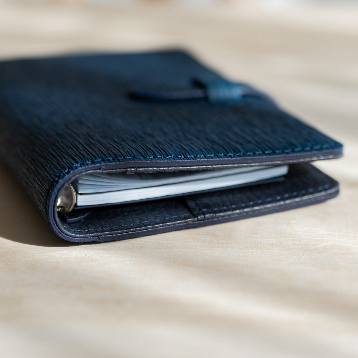 Navy Ise Gikakushi planner closed, side view of the rings and pale blue page edges