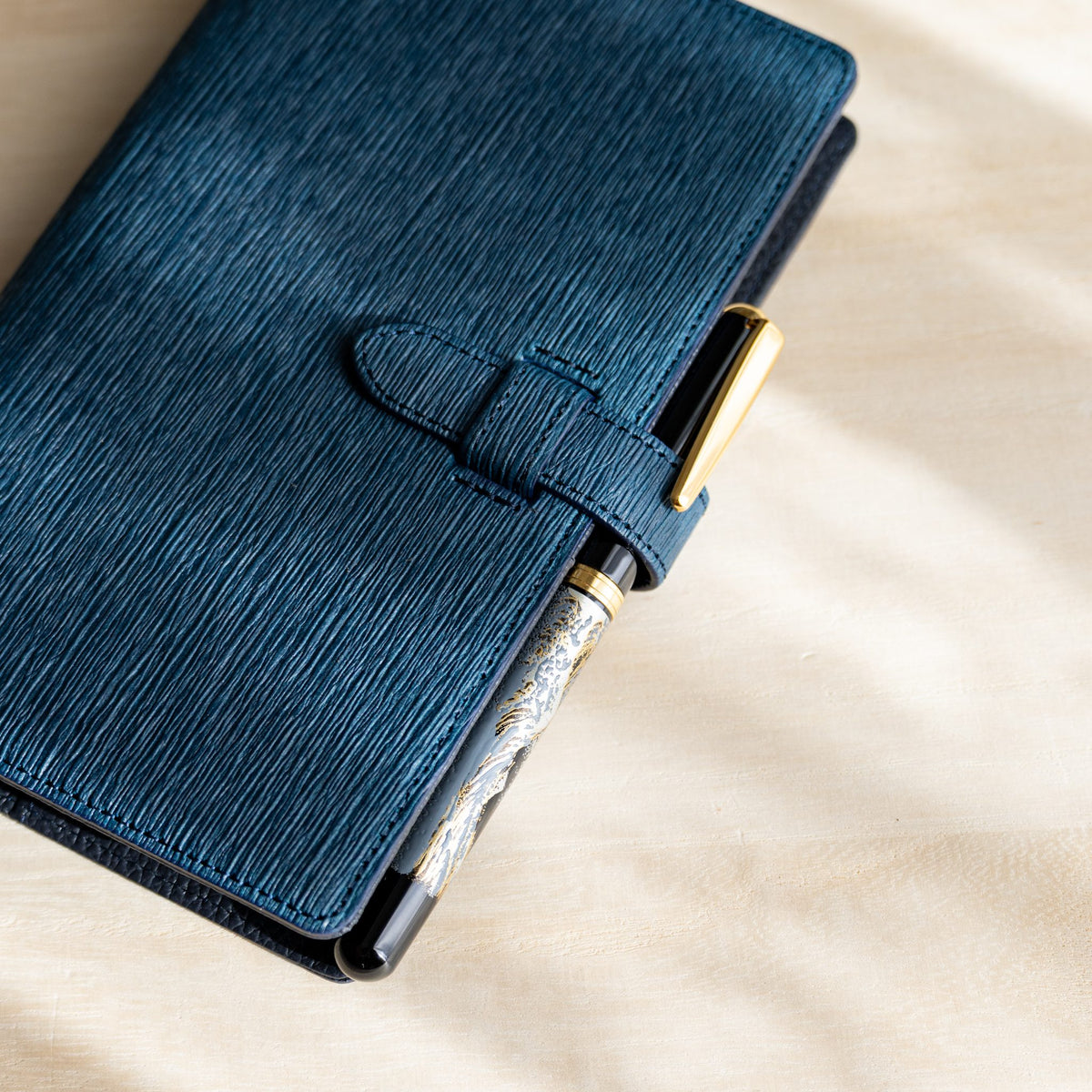 Navy Ise Gikakushi planner with a fountain pen held under the belt strap