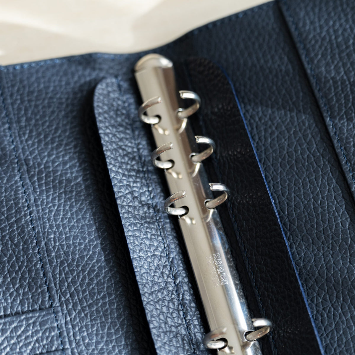 Silver rings opened on the binder mechanism, navy pebbled leather lining with blue stitching
