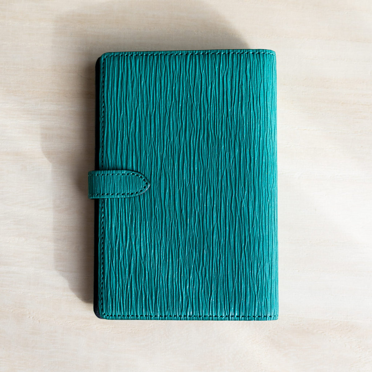 Teal Ise Gikakushi paper leather planner, back cover with the strap tab on the left side