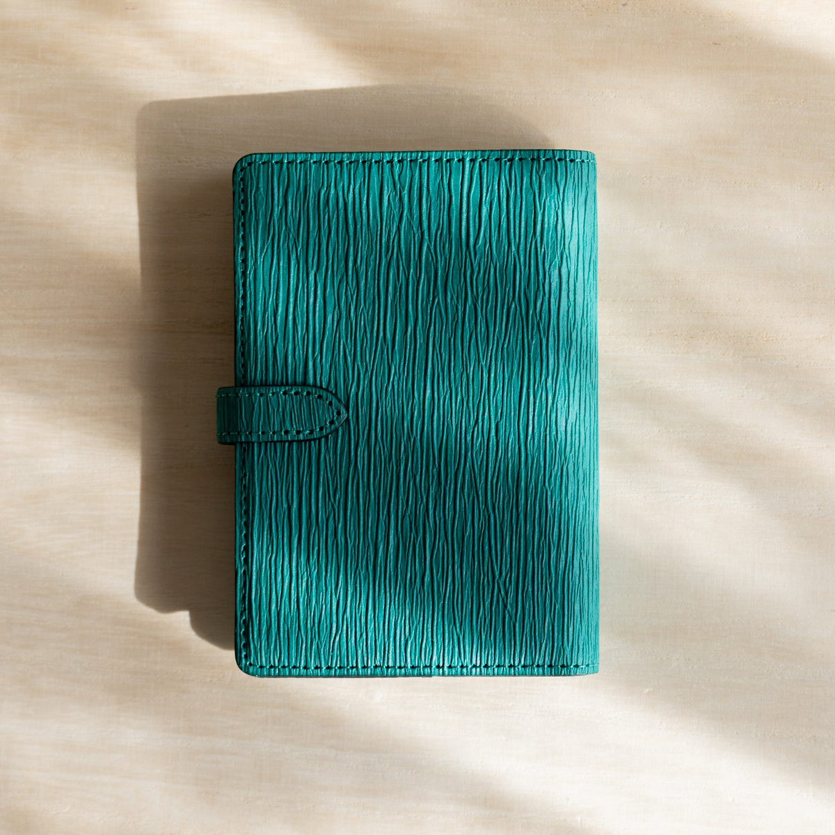Teal Ise Gikakushi paper leather planner, back cover with the strap tab on the left