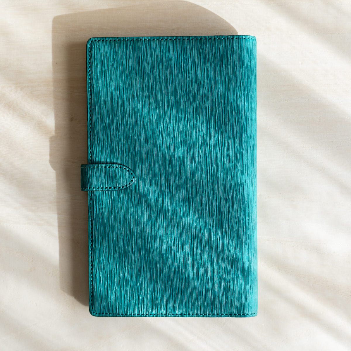 Teal Ise Gikakushi paper leather planner, back cover with vertical crease texture and strap tab