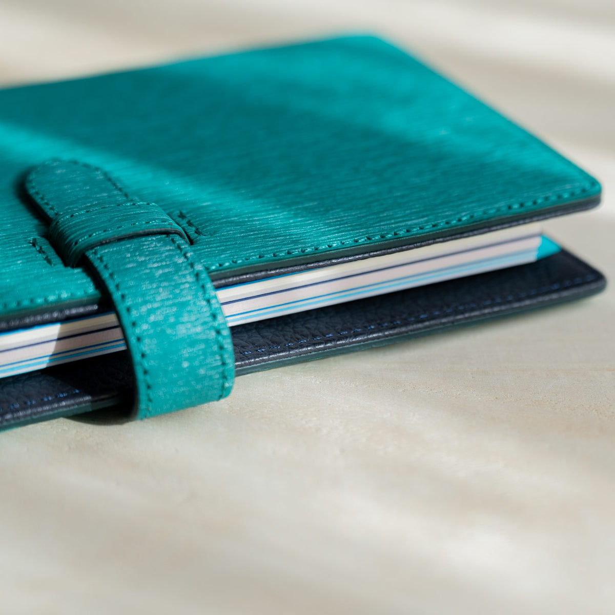 Teal Ise Gikakushi paper leather planner closed with belt strap, Mermaid Assorted Blues index tabs at the page edge
