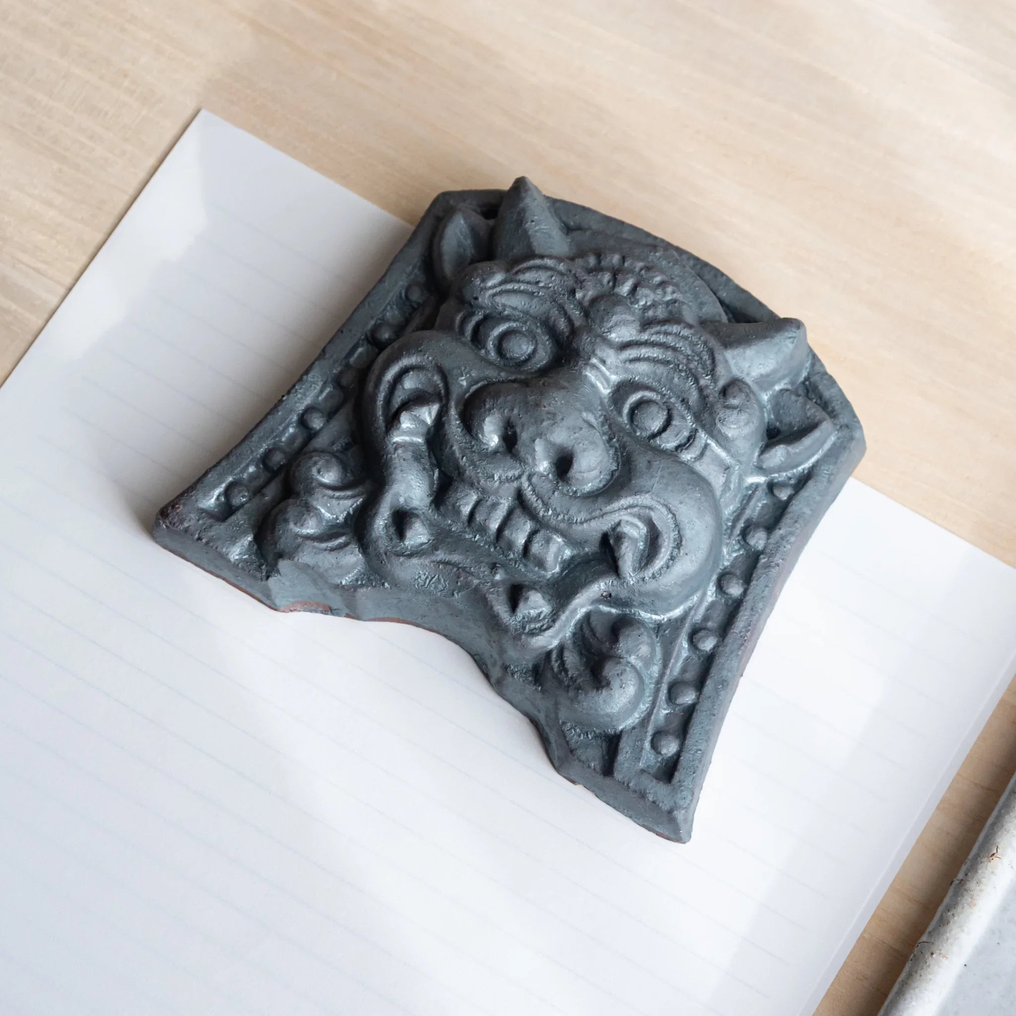 Japanese Kawara large roof guardian ceramic paperweight with resolute expression shown displayed in composition