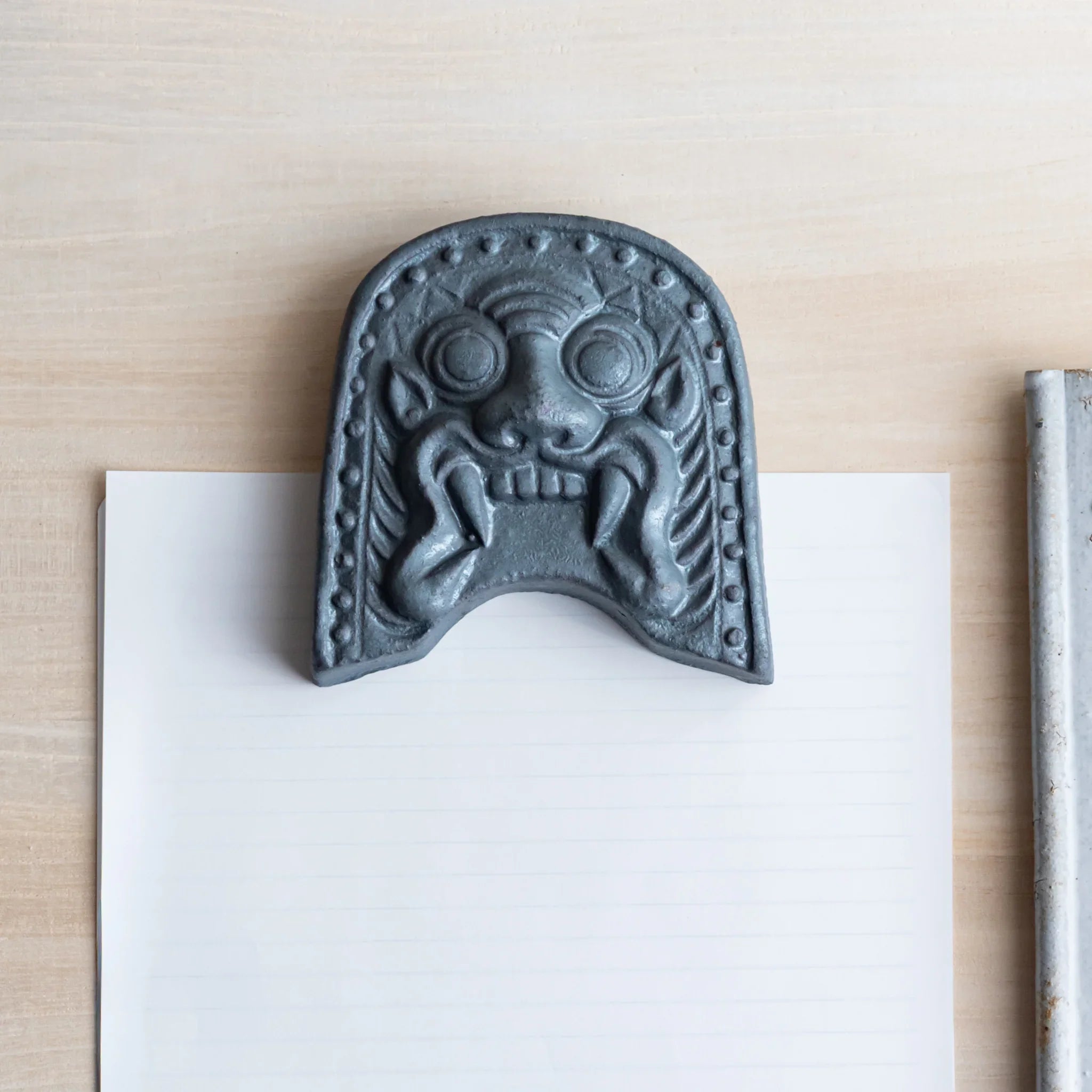 Onigawara-motif Japanese paperweight. A front-view shot of the desk accessory resting prominently on a sheet of paper.