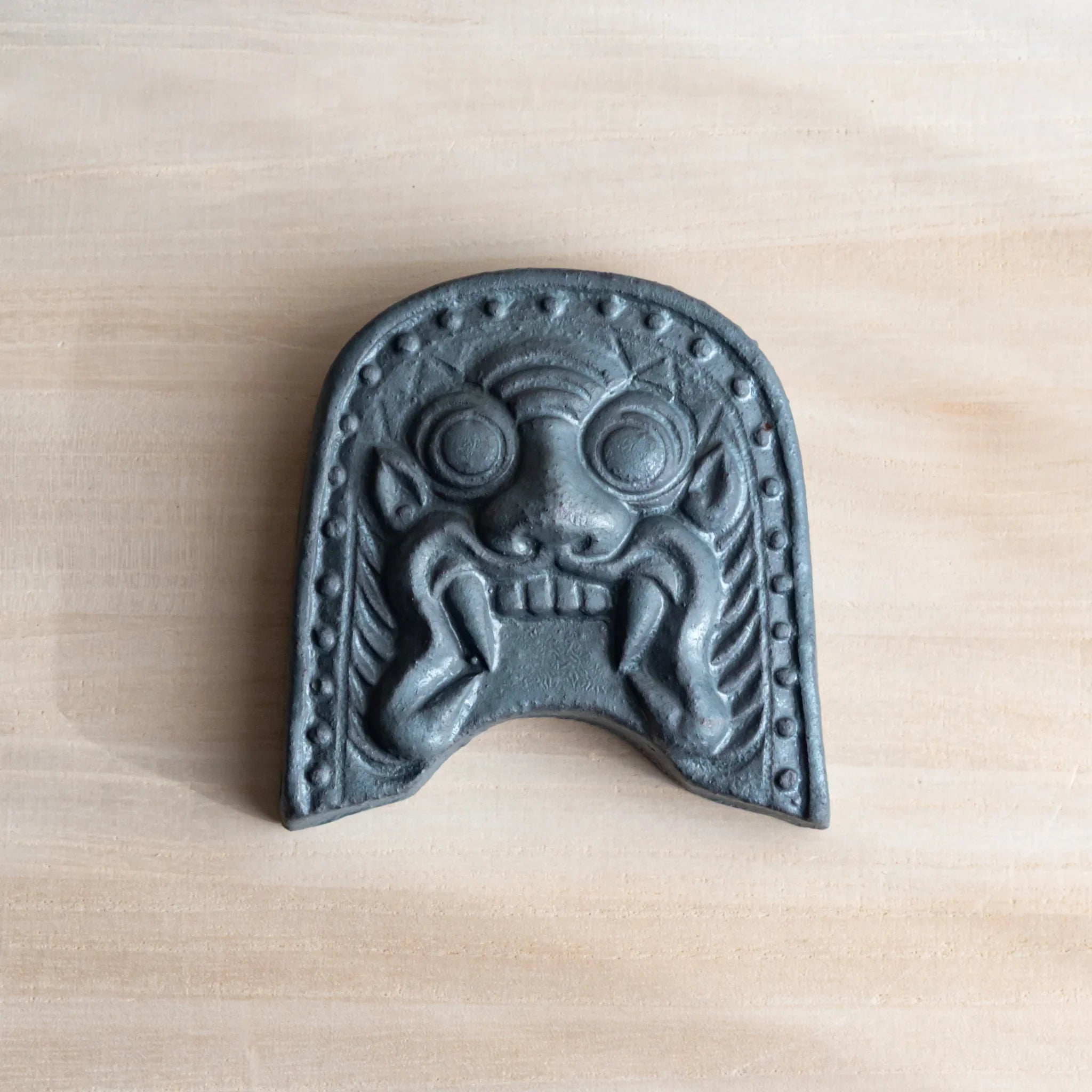 Japanese Paperweight inspired by Oni-gawara roof tiles resting on paper, handcrafted as a refined Japanese Desk Accessory.