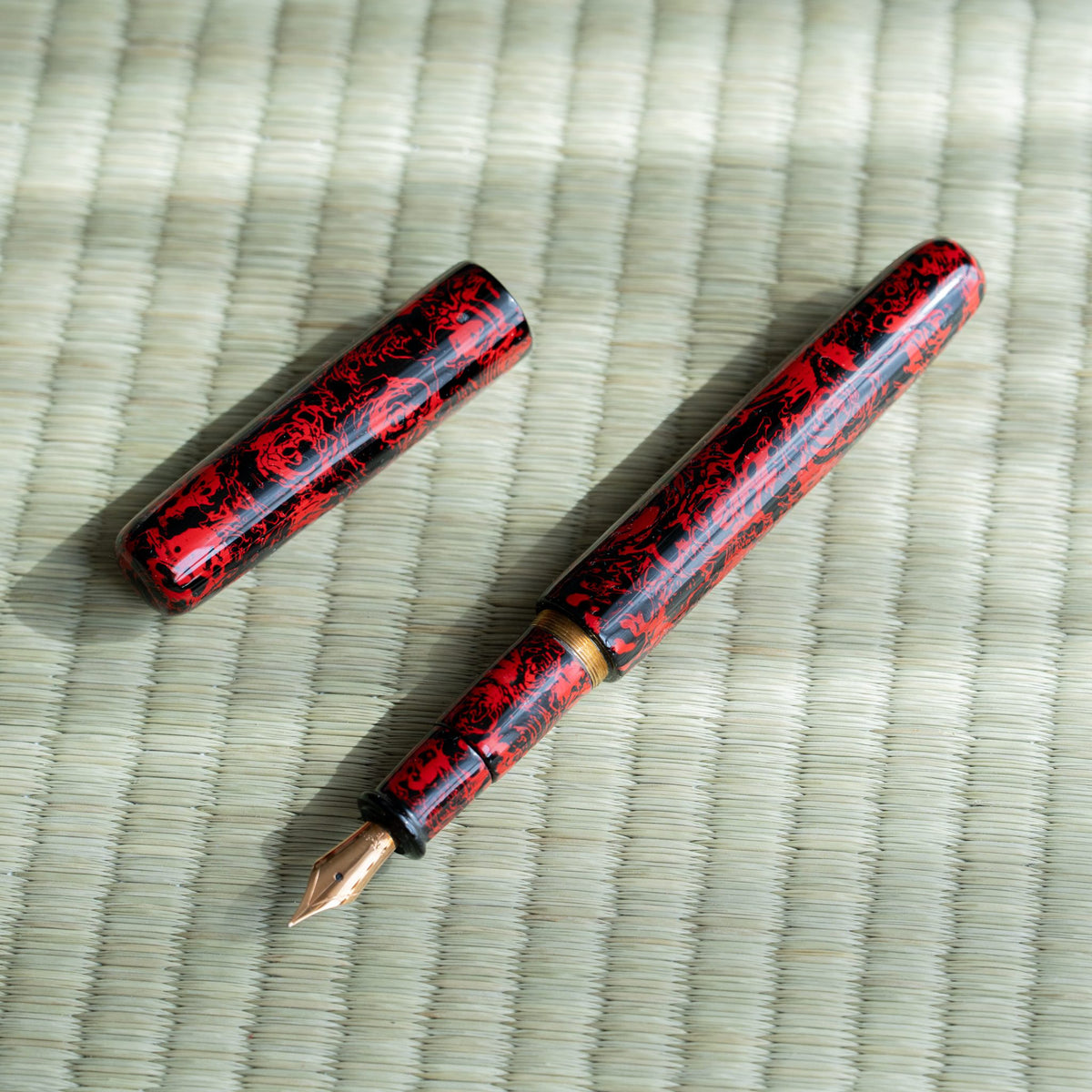 Kagaribi Tsugaru-nuri fountain pen uncapped beside its cap, gold-colored nib, brass threads and red-black barrel