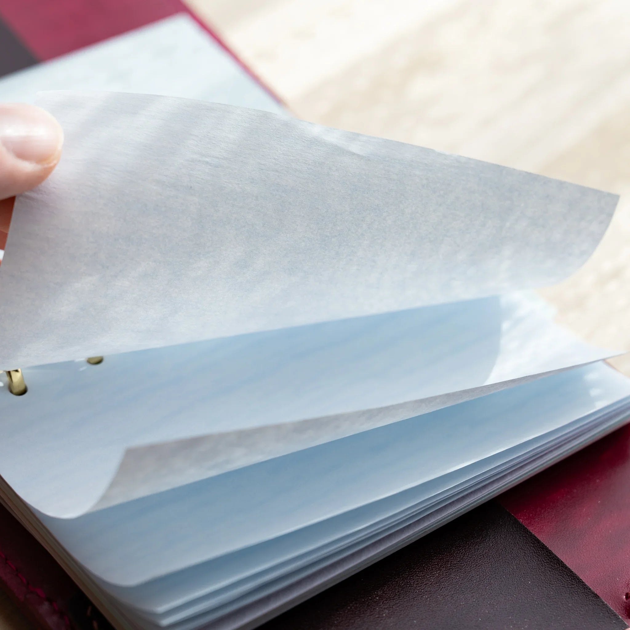 Japanese Stationery onion skin refill page being lifted by hand, showing its thin translucent sheet over stacked mini 6 pages.