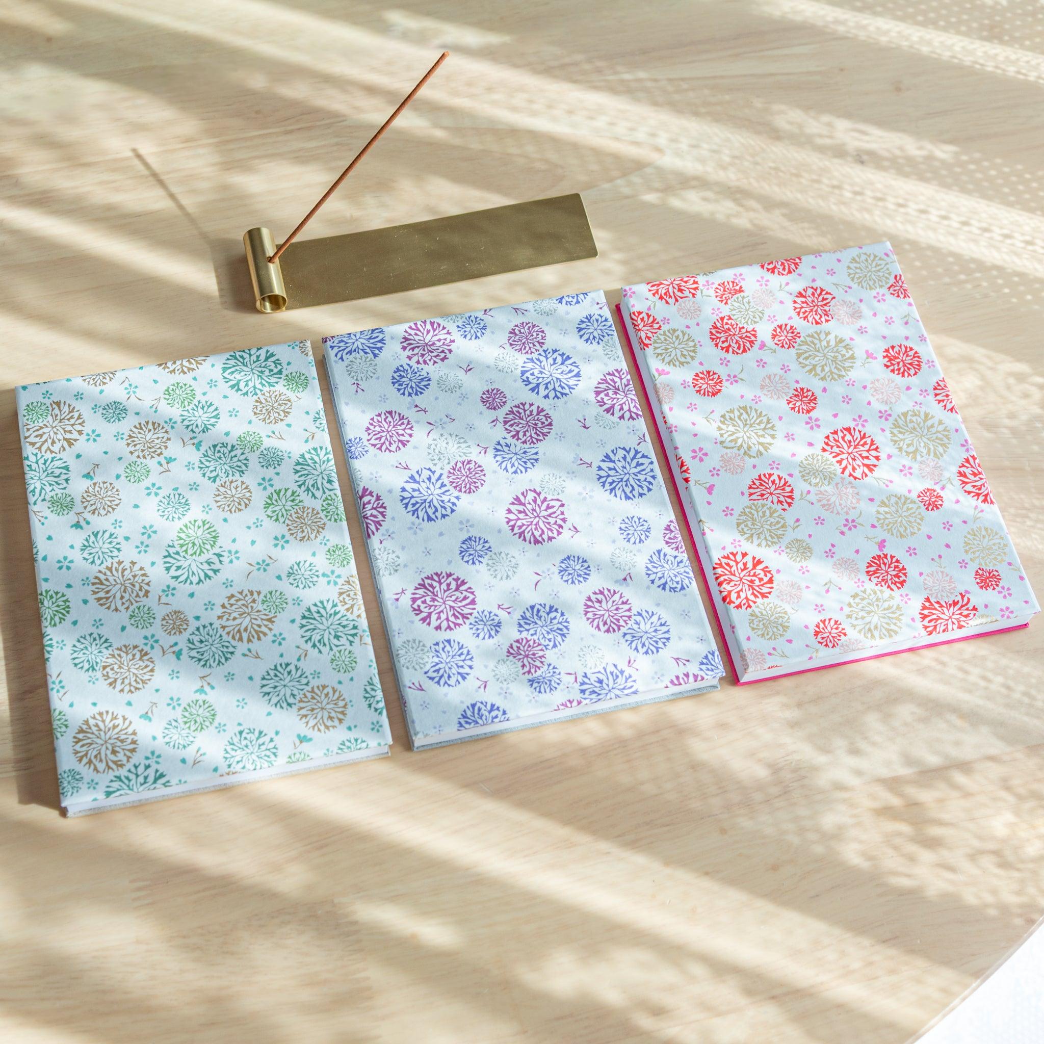 Three Kikka Harmony washi Goshuincho stamp books in red, blue, and green on desk – Japanese stationery